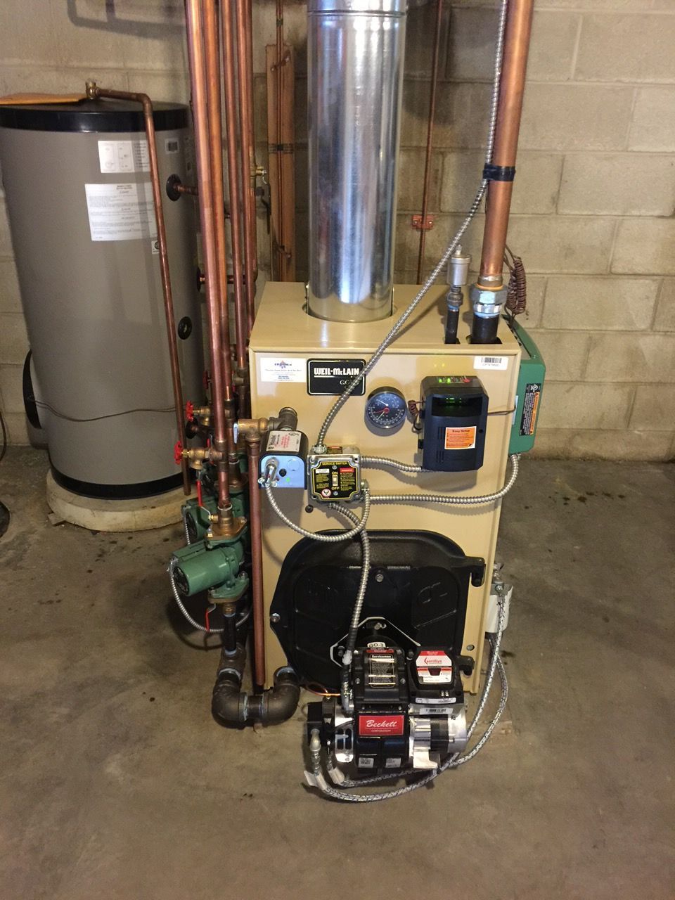 Basement utility room with two water heaters, furnace, and exposed copper pipes under the joists