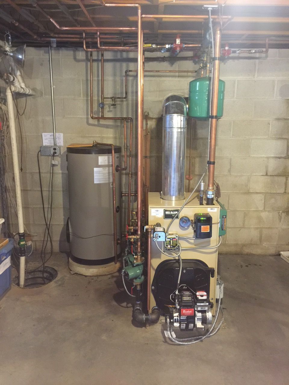Basement utility room with water heater, furnace, pipes, and electrical equipment against cinderblock walls