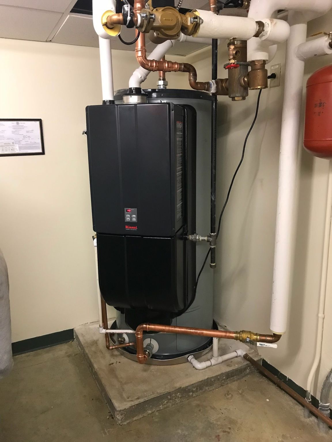 Outdoor central air conditioner unit beside a house, on a concrete pad near brick edging and shrubs
