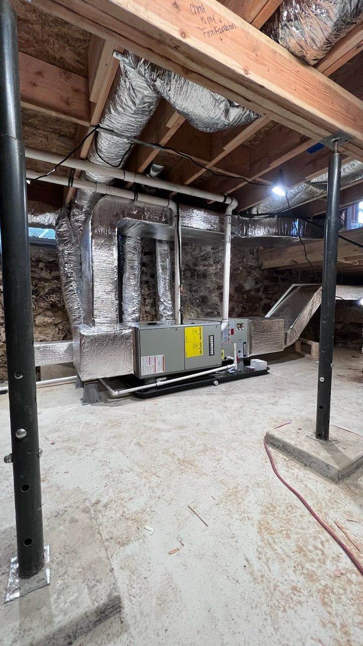 Basement utility room with water heater, boiler, pipes, and pumps along the wall.