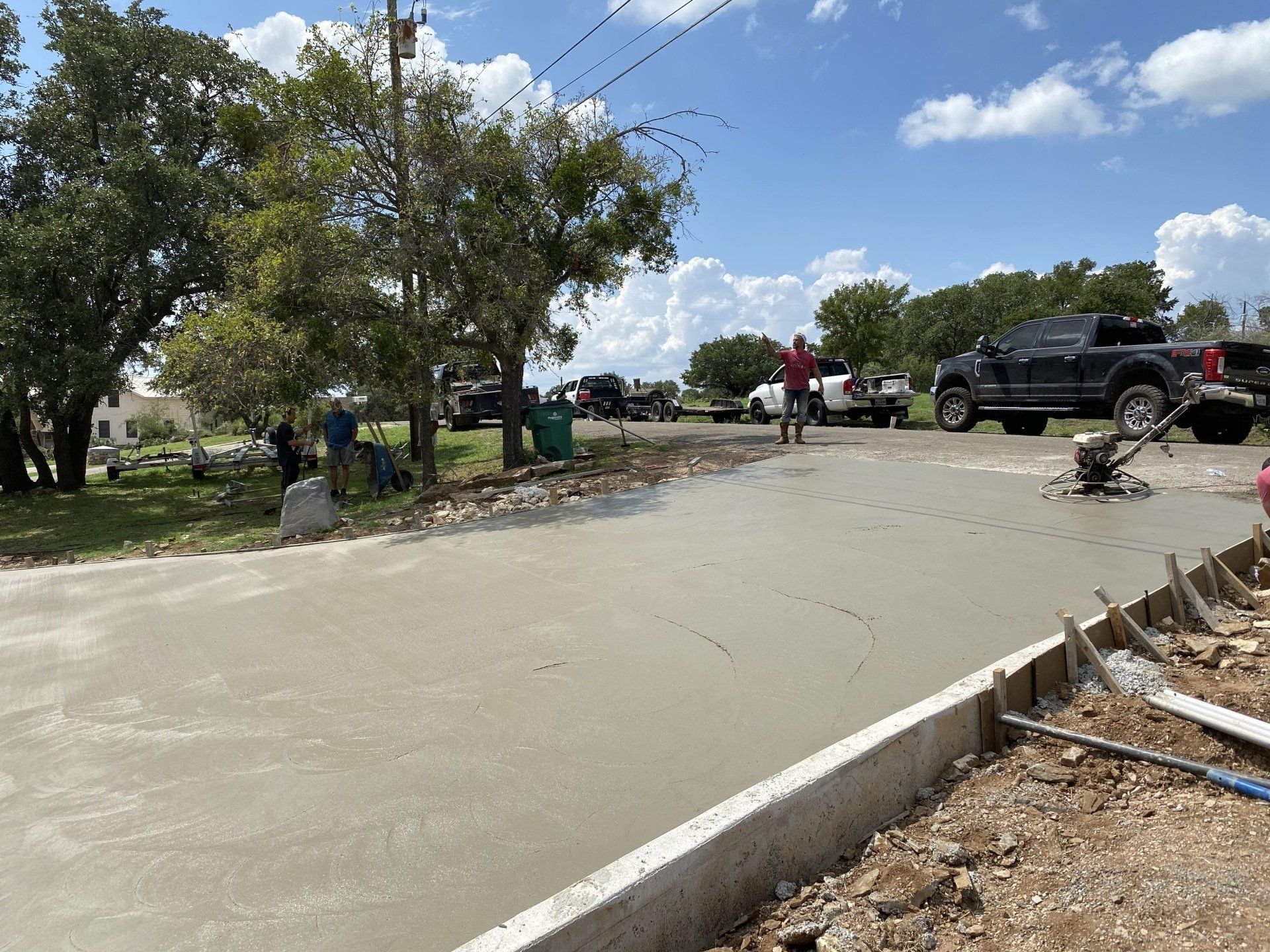 A group of people are working on a concrete driveway.