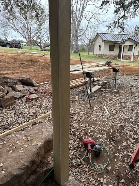 A wooden post is sitting in the dirt in front of a house under construction.