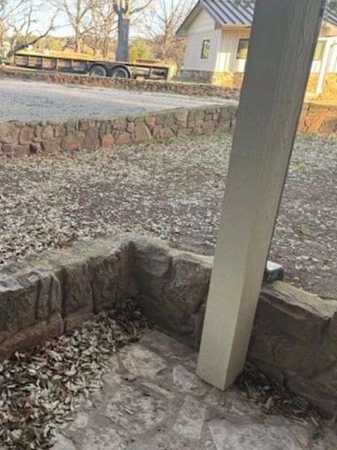 A white pole is sitting next to a stone wall.