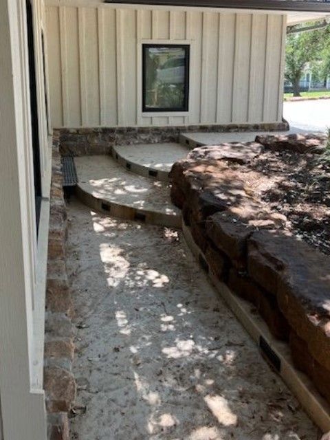 A stone walkway leading to a house with steps and a window.