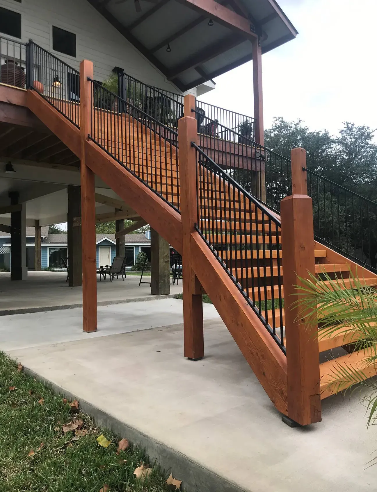 A wooden staircase leading up to a deck with a metal railing