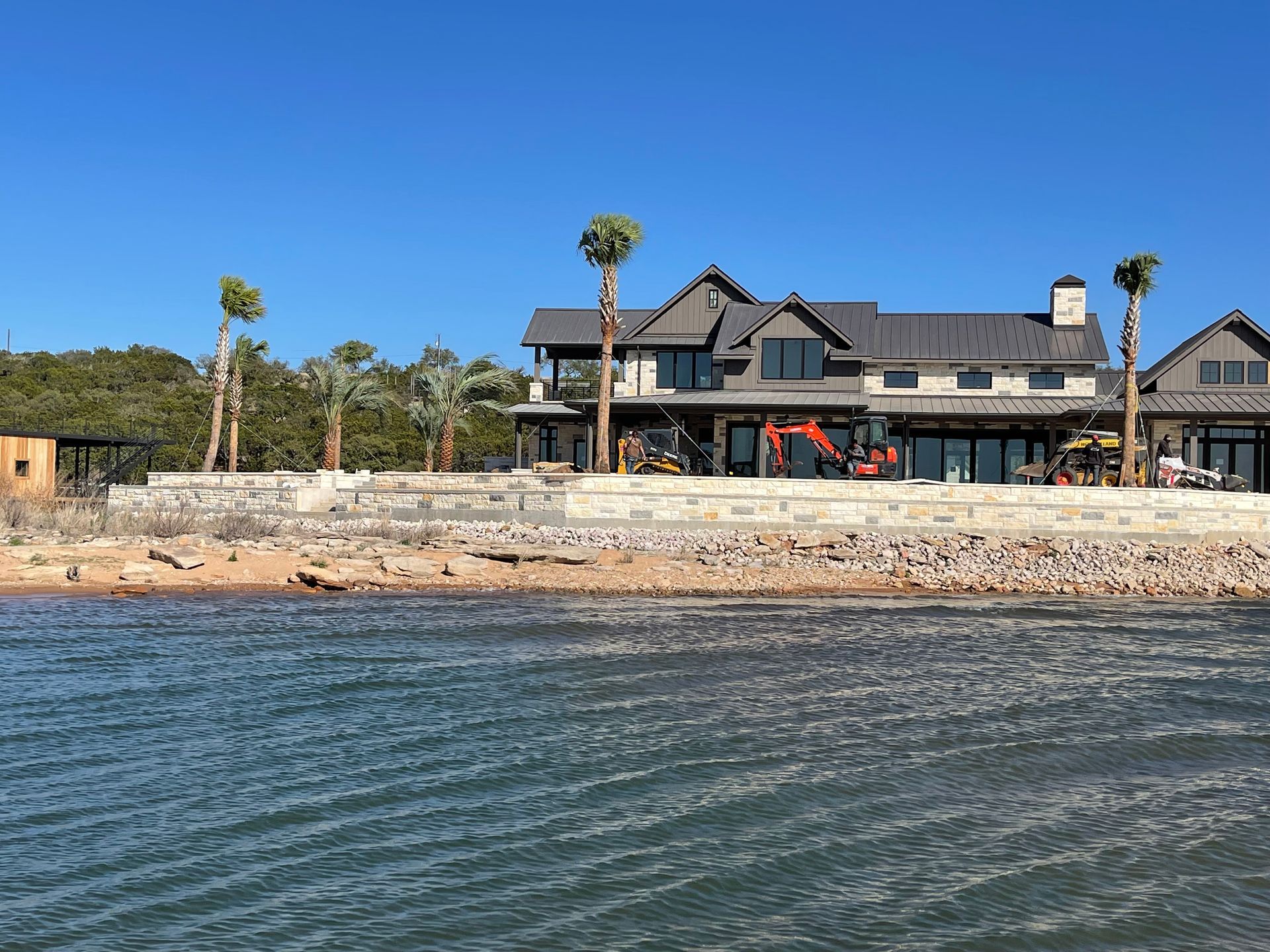 A large house is sitting on the shore of a body of water.