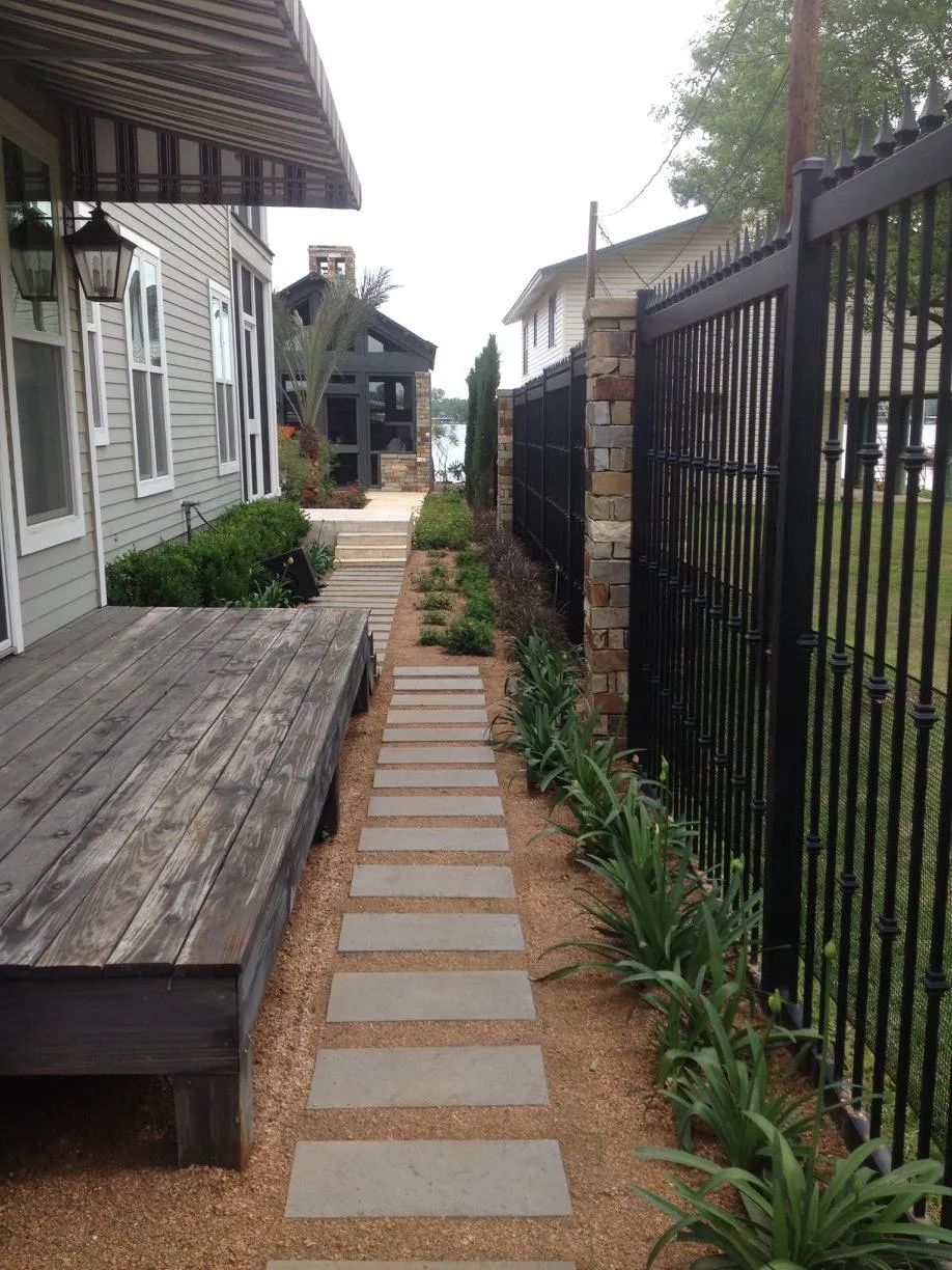 A walkway leading to a house with a black fence