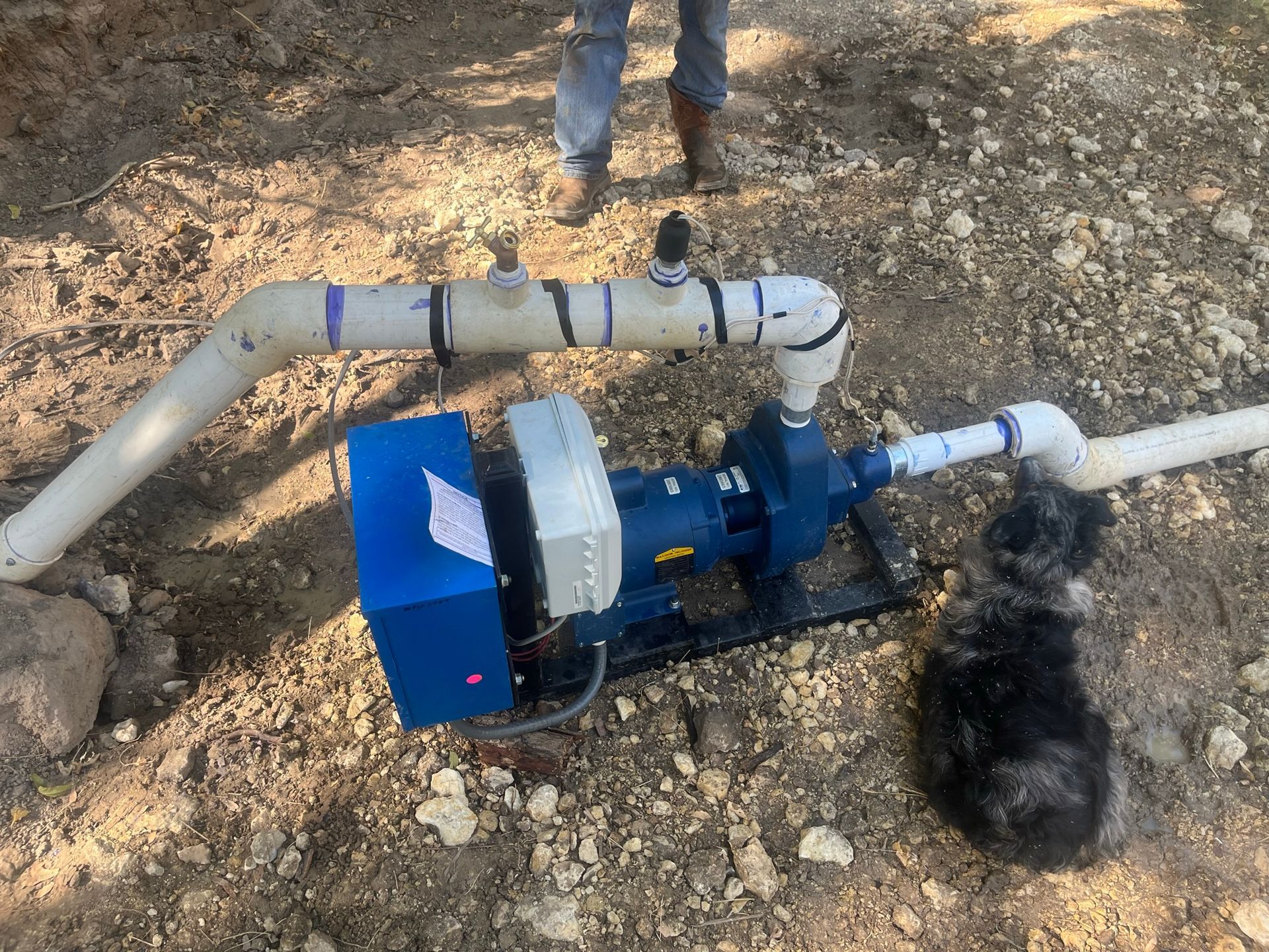 A pump is sitting on the ground next to a pipe.