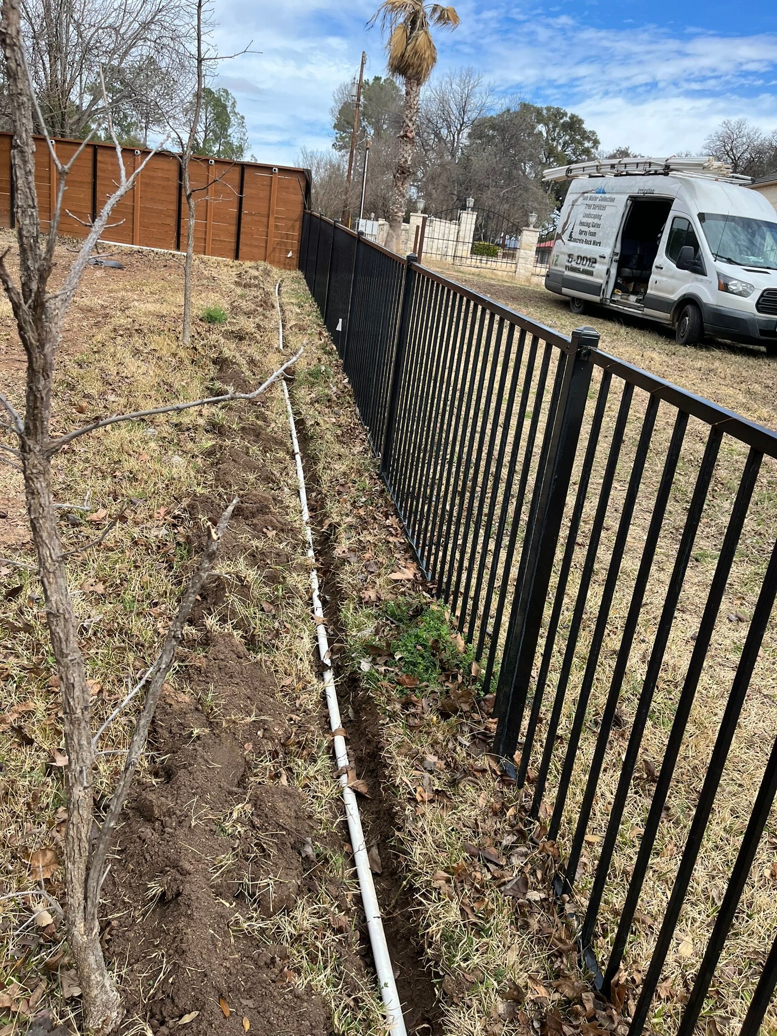 A black fence with a white van parked next to it.