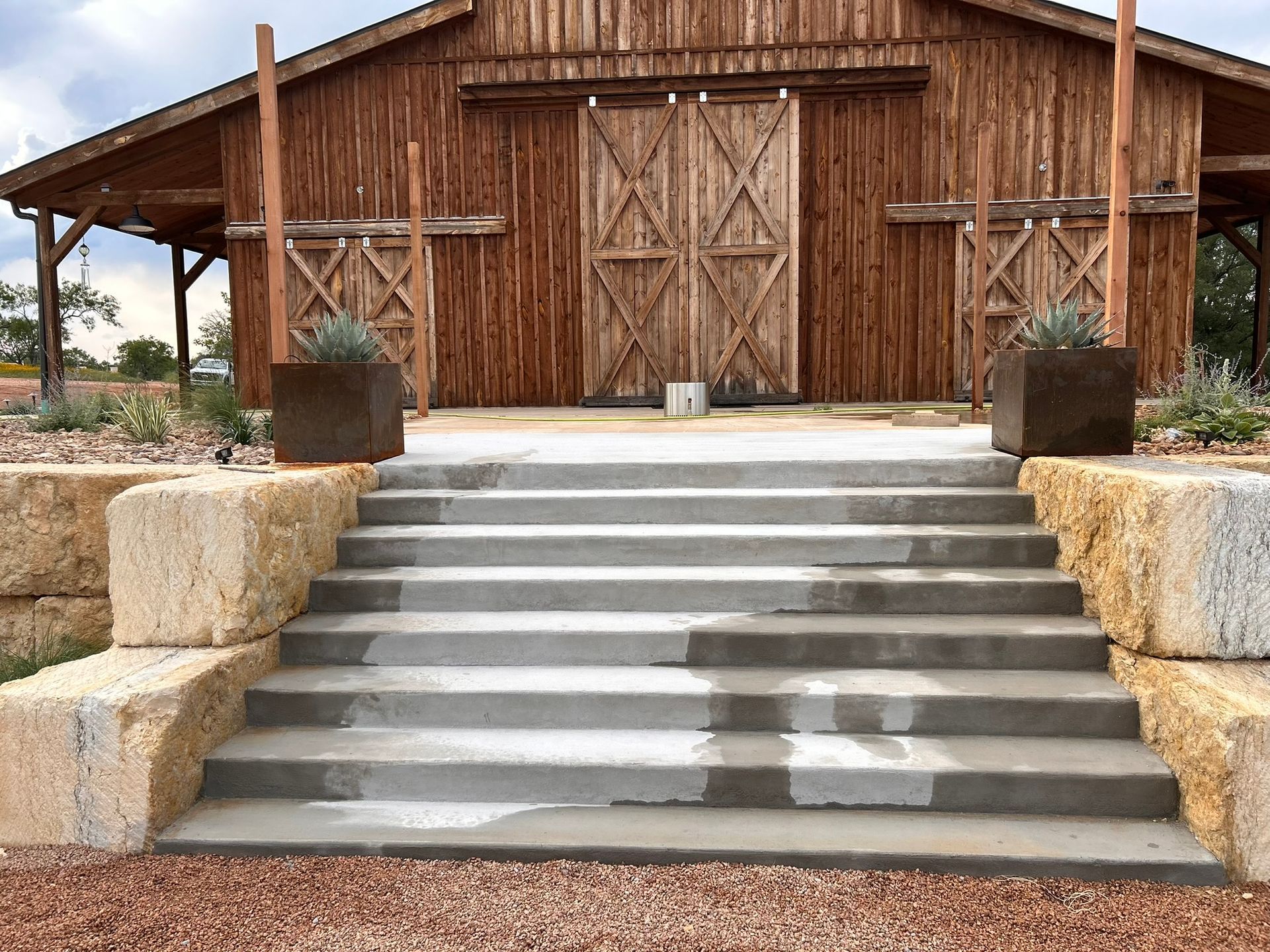 A wooden barn with concrete steps leading up to it.
