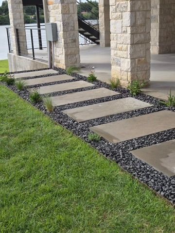 A lawn with a walkway made of concrete and gravel.