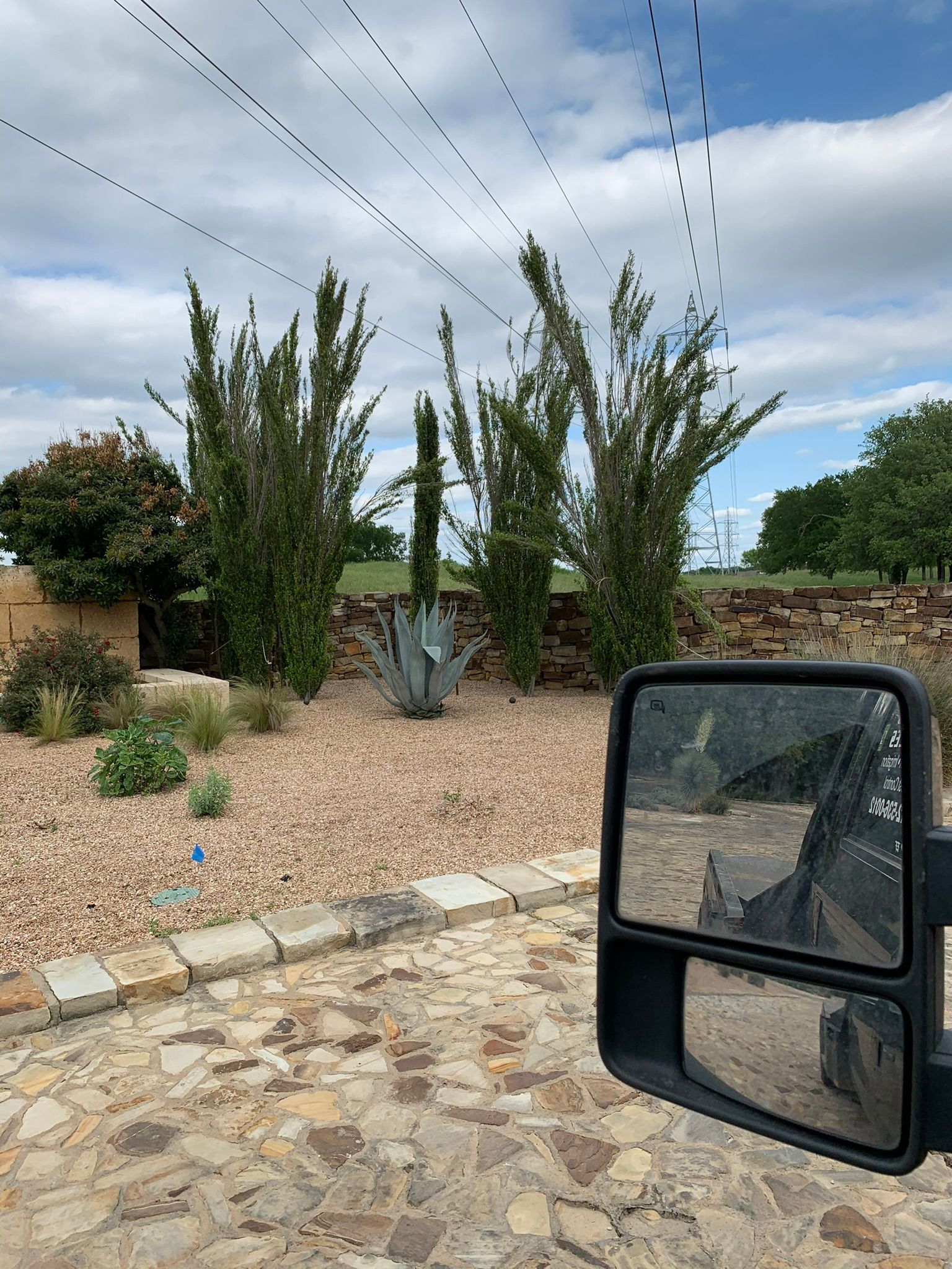 A truck is parked on a gravel road next to a side mirror.