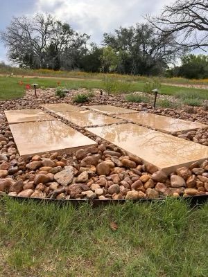 A row of stone walkways surrounded by rocks in a grassy field.