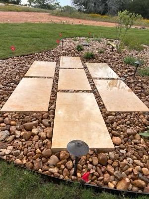 A stone walkway surrounded by rocks and grass in a yard.