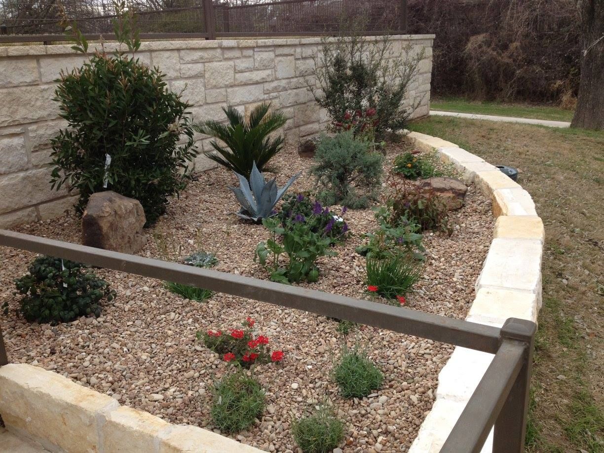 A garden with rocks and plants surrounded by a stone wall