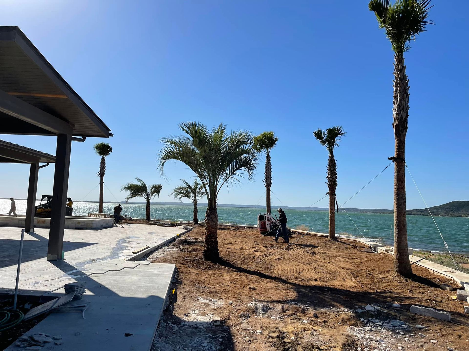 A group of people are standing on a beach near a body of water.
