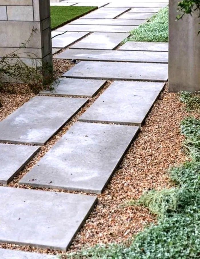 A concrete walkway with gravel and grass on the side