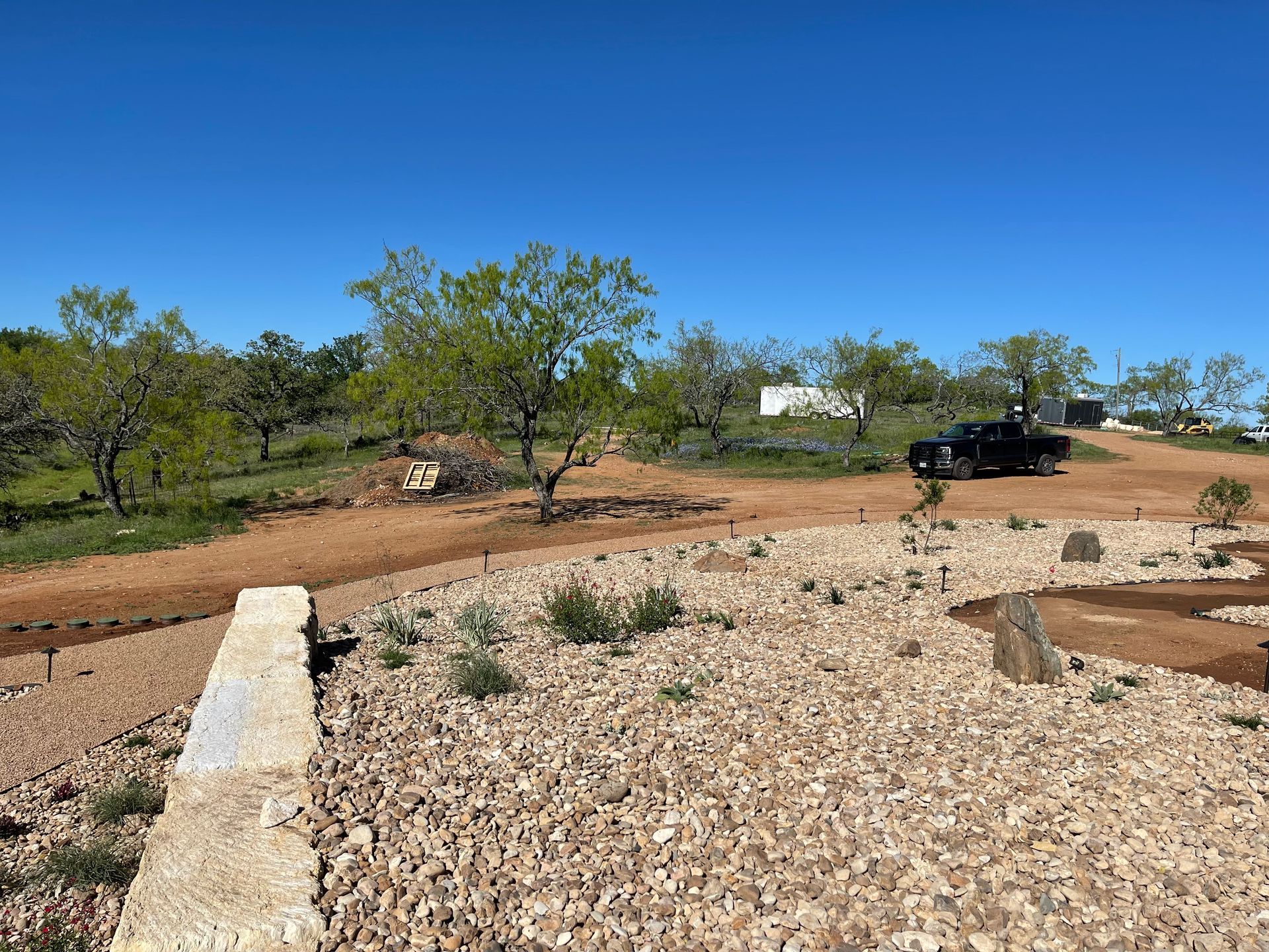 A truck is parked on the side of a dirt road.