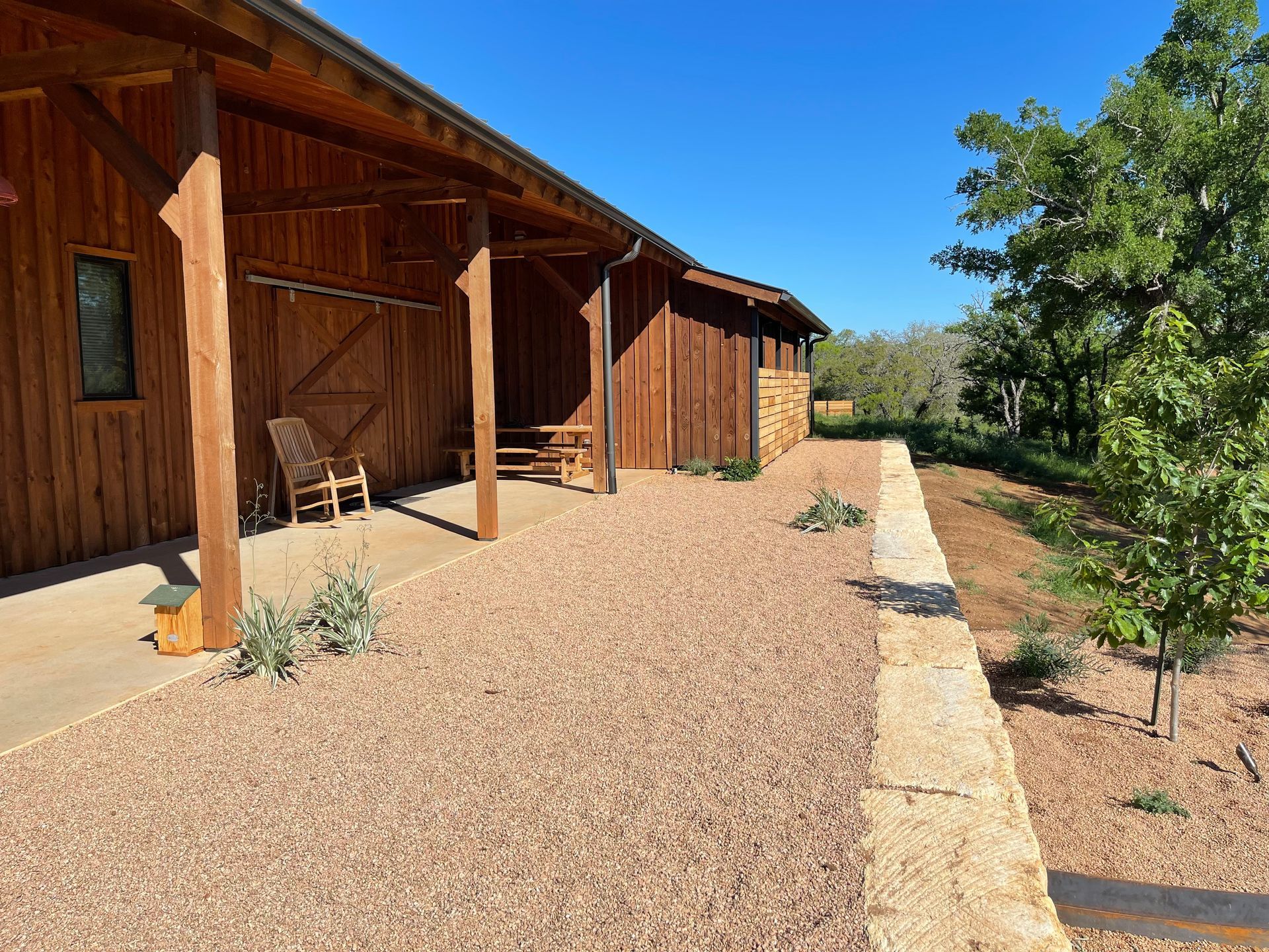 A wooden house with a porch and chairs in front of it.