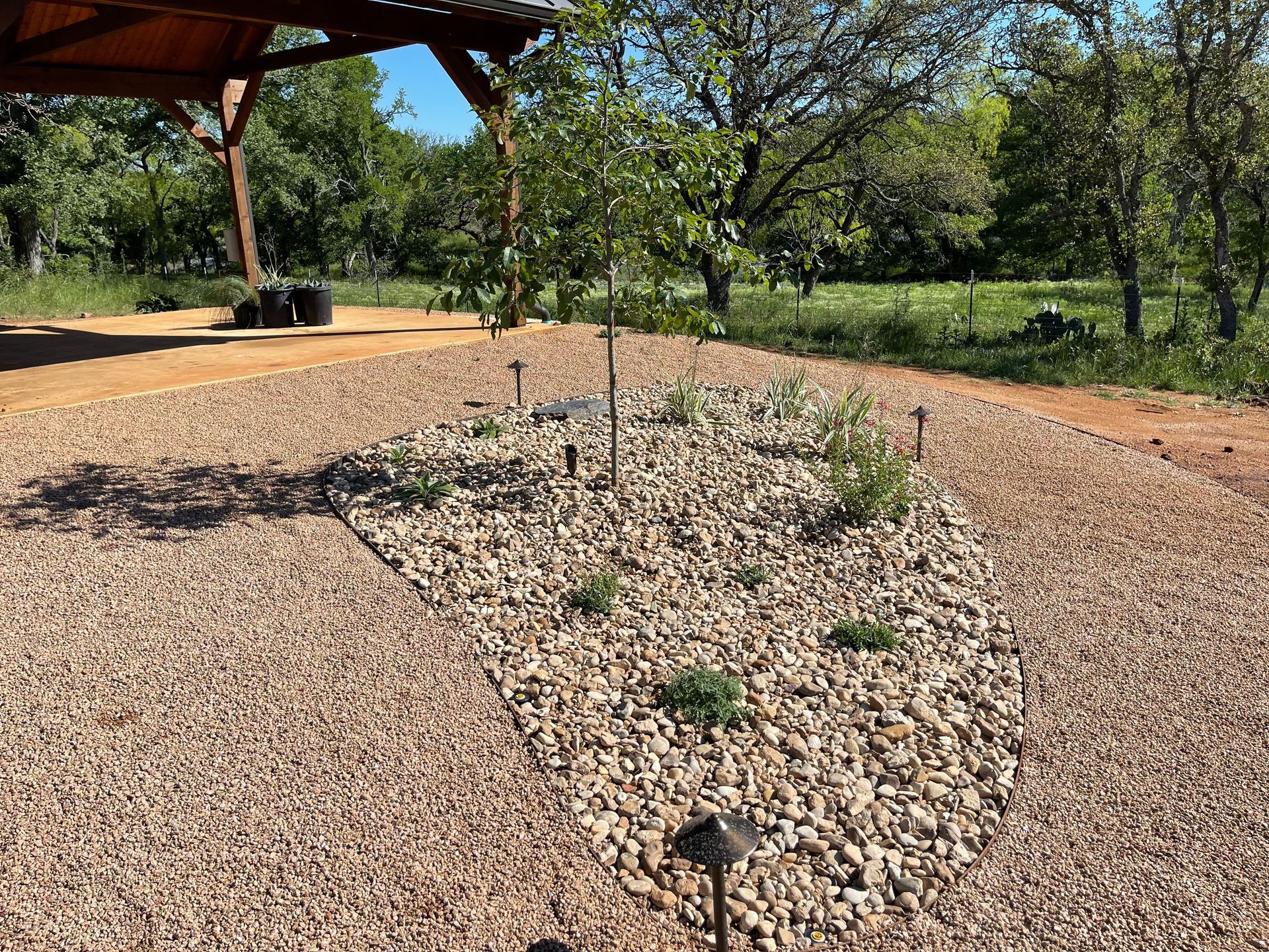 A gravel driveway with a gazebo in the background and trees in the background.