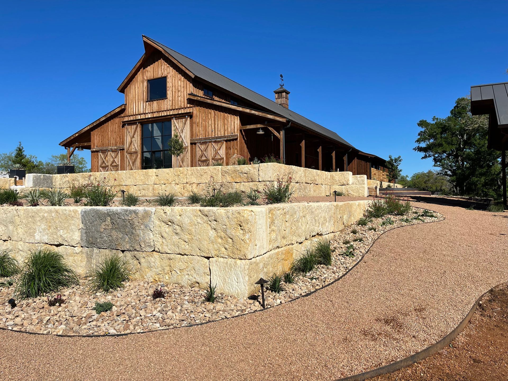 A large wooden barn is sitting on top of a rocky hill.