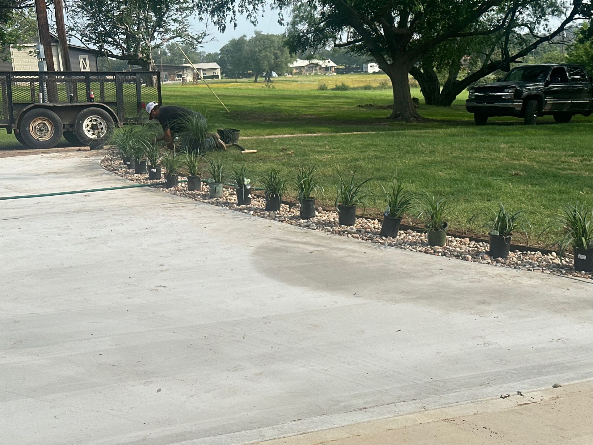 A man is planting plants in a driveway next to a truck