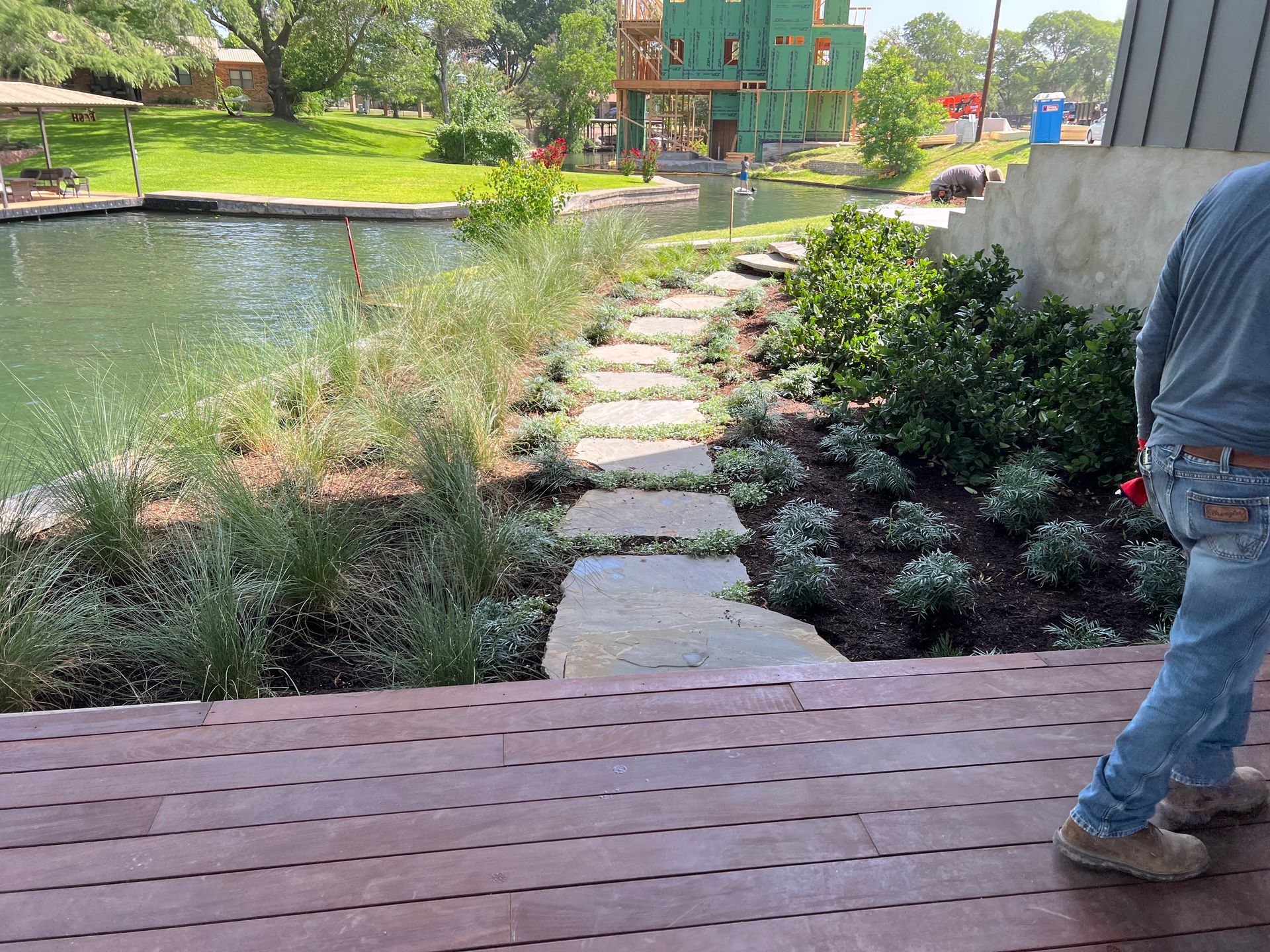 A man is walking down a wooden deck next to a pond.