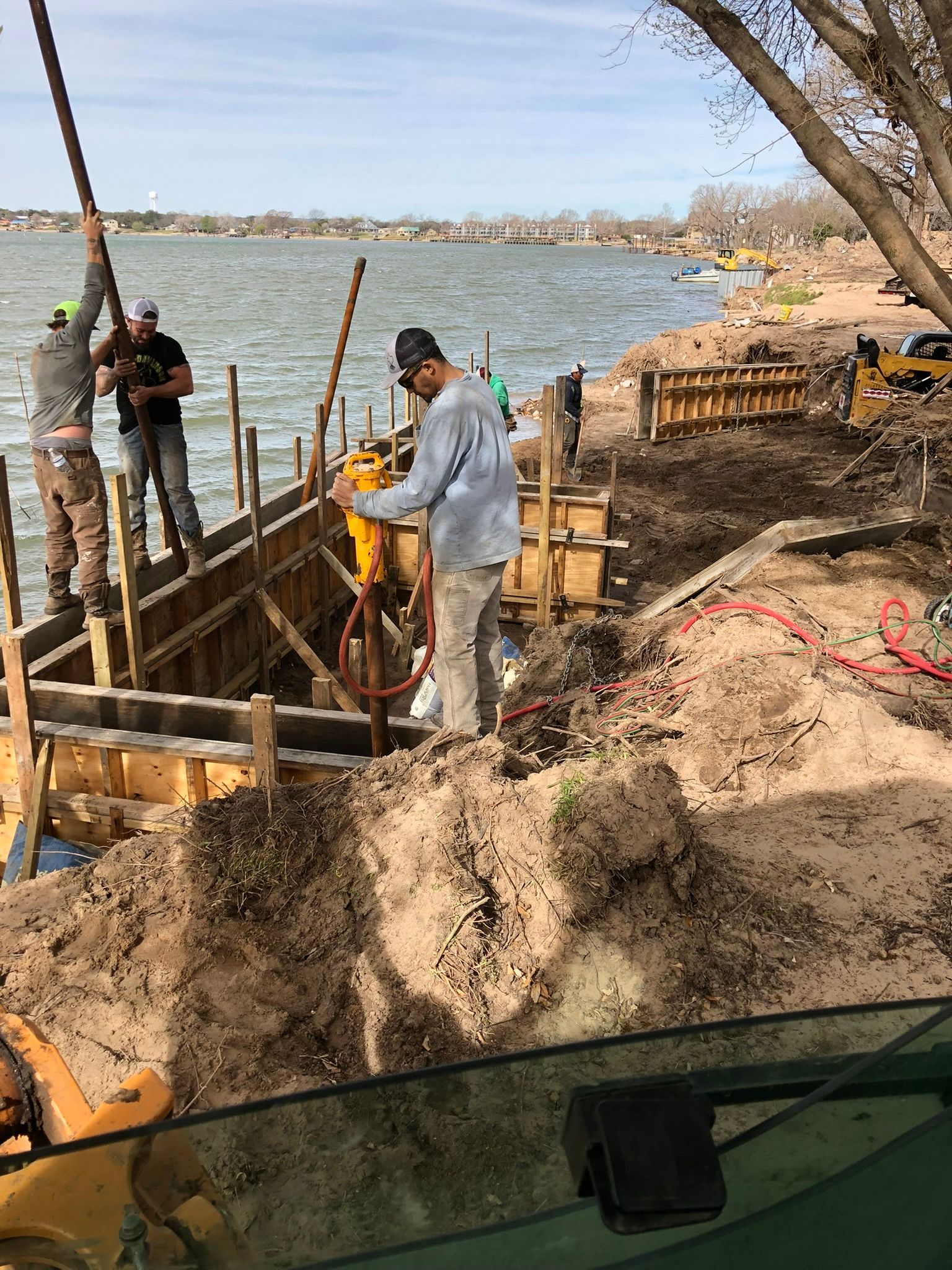 A group of men are working on a construction site next to a body of water.
