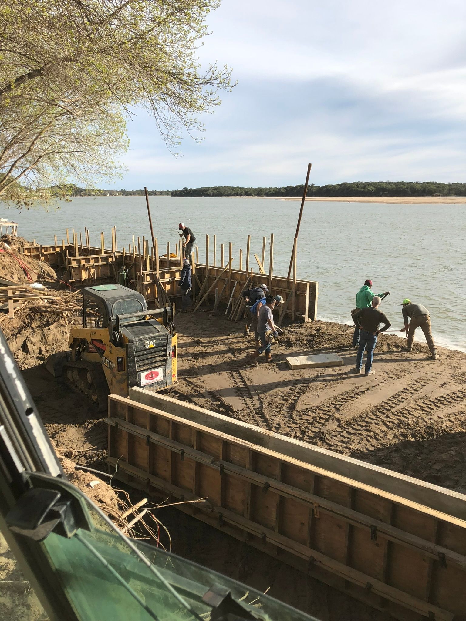 A group of people are working on a construction site next to a body of water.