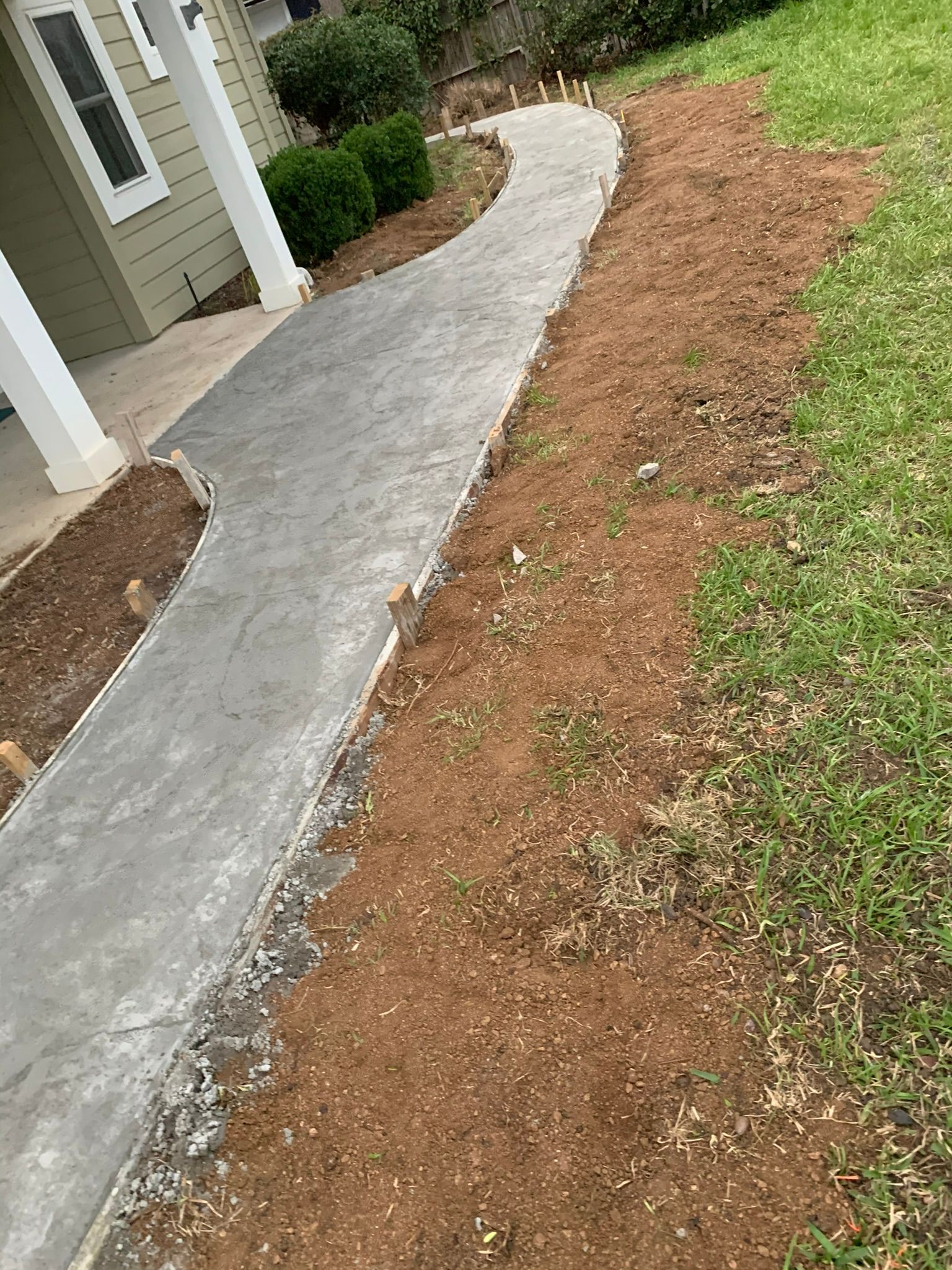 A concrete walkway is being built in front of a house.