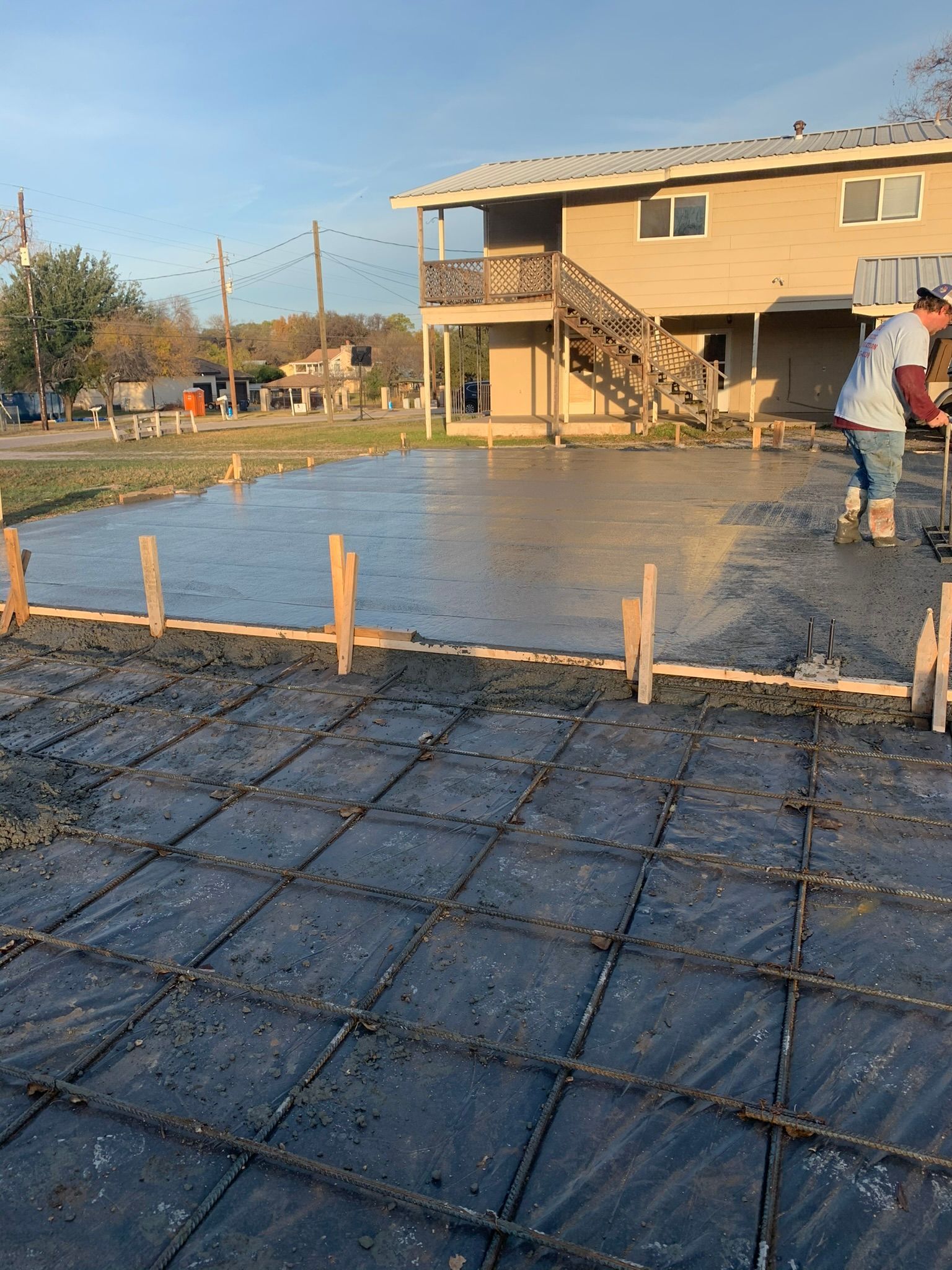 A man is pouring concrete in front of a house.