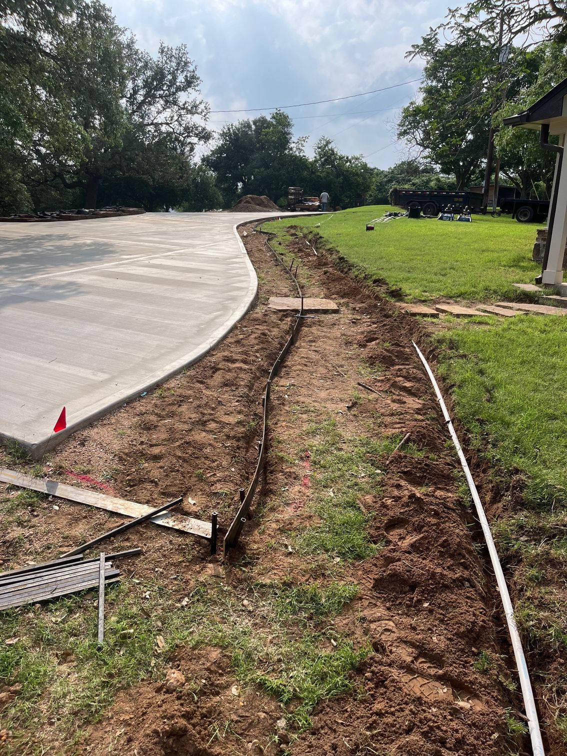 A concrete driveway is being built next to a grassy field.