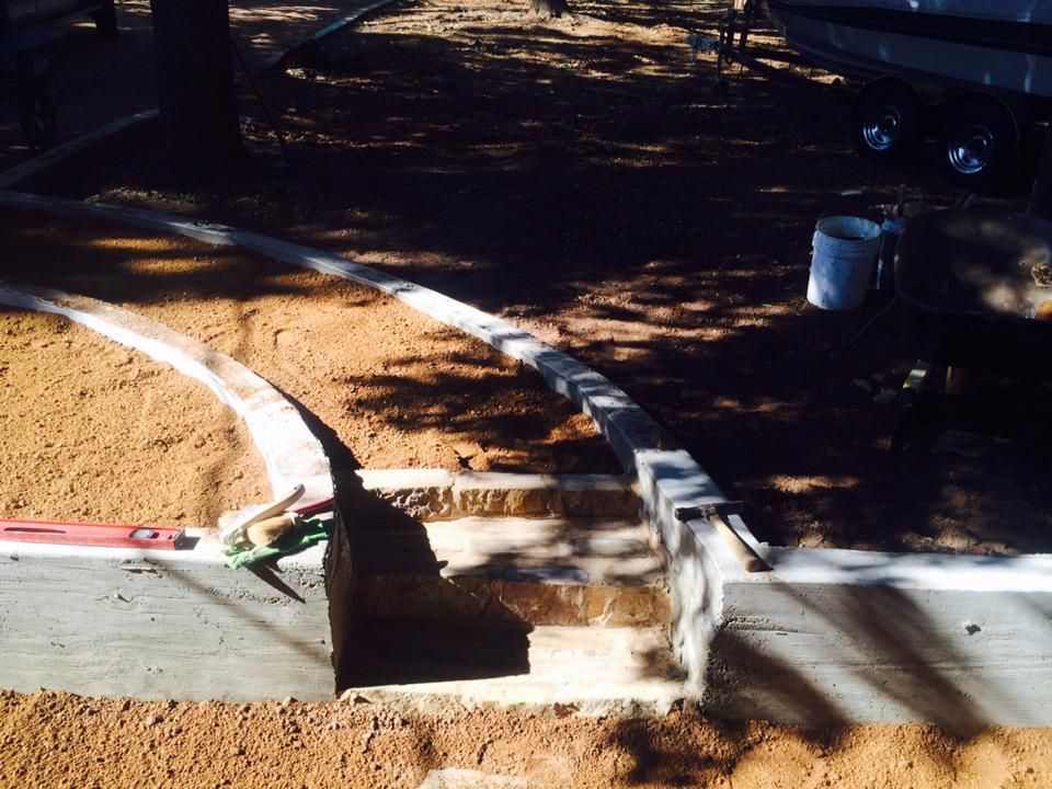 A concrete curb is being built on a dirt road