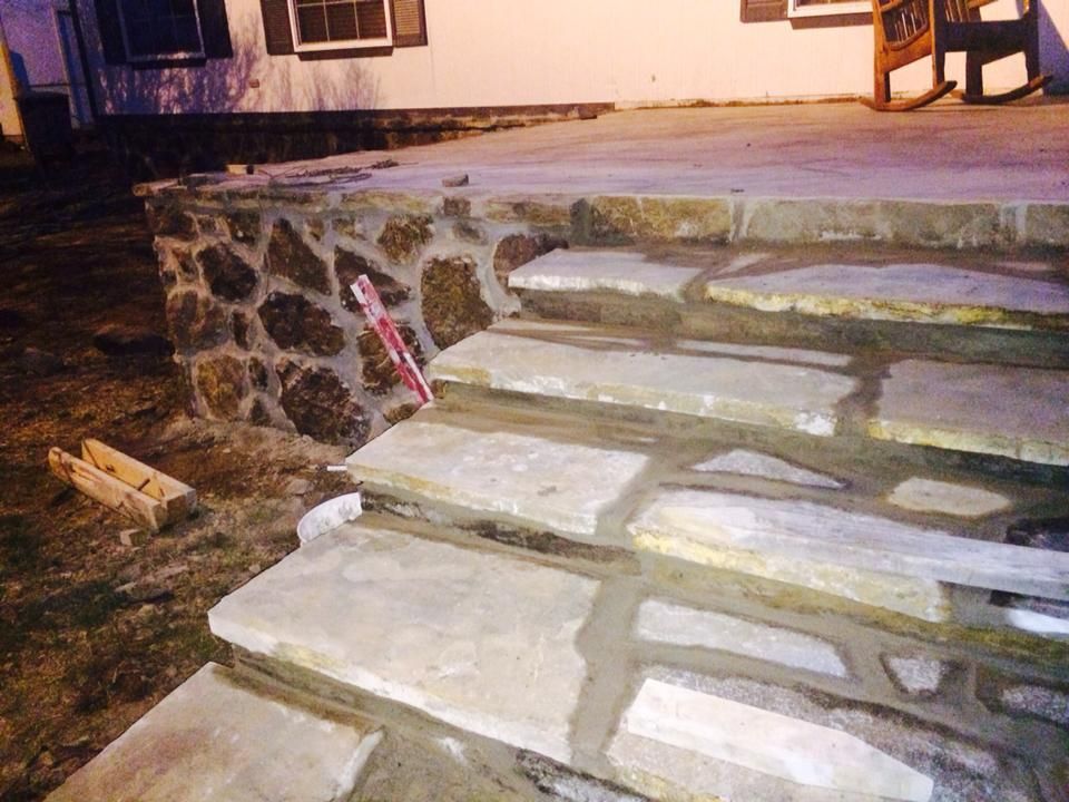 A rocking chair is sitting on a porch next to a set of stone steps.