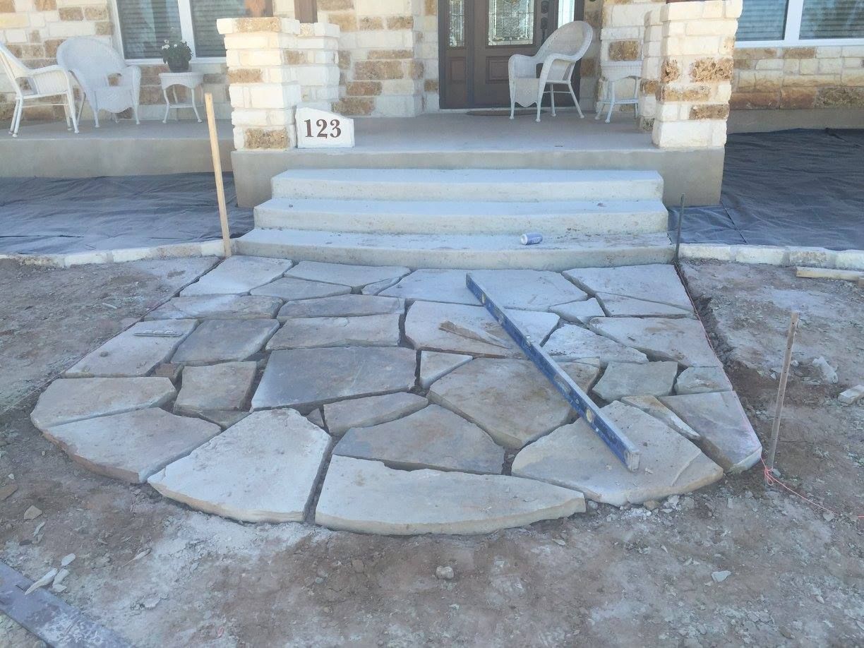 A stone walkway is being built in front of a house.