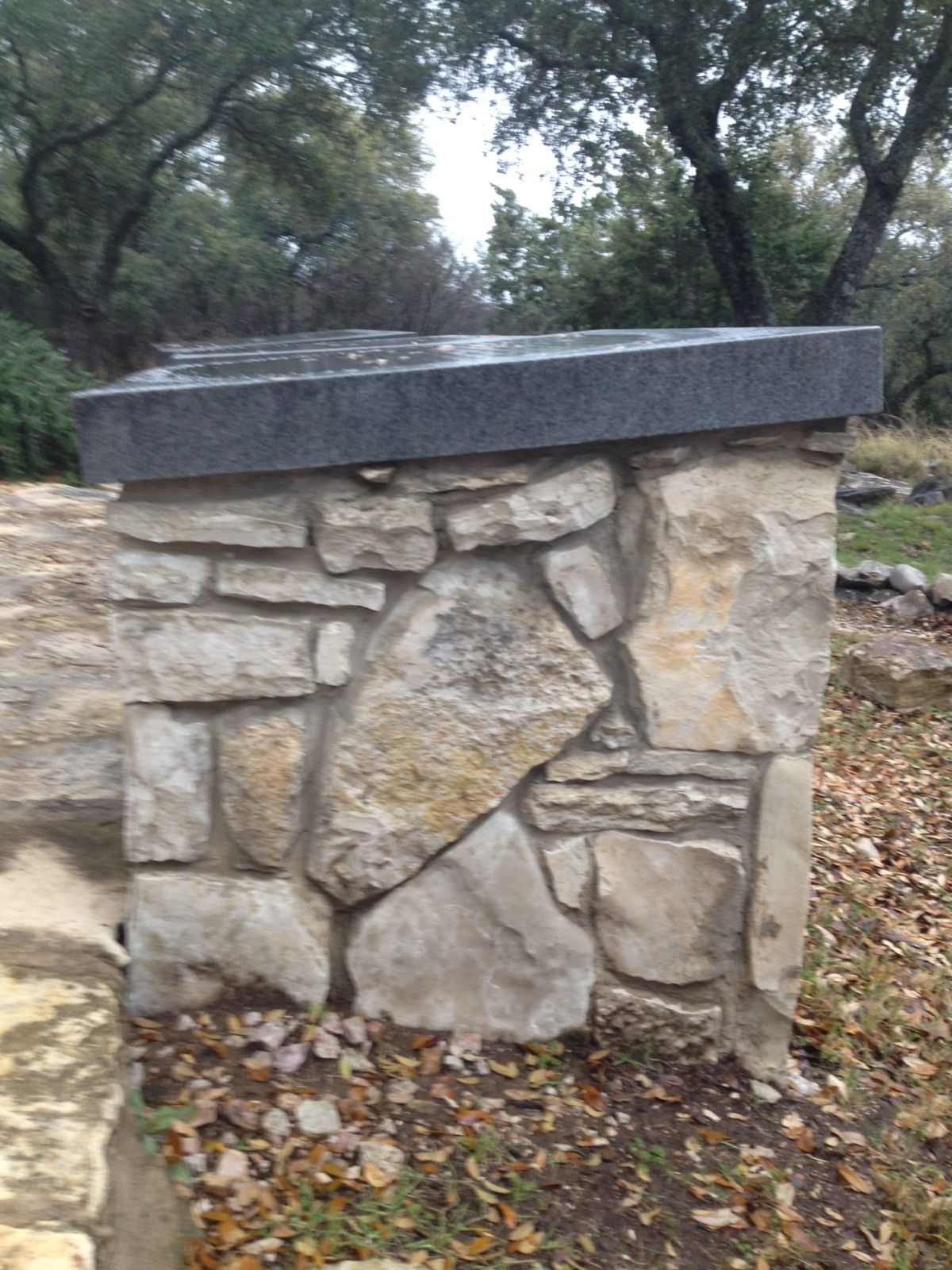 A stone wall with a black ledge on top of it