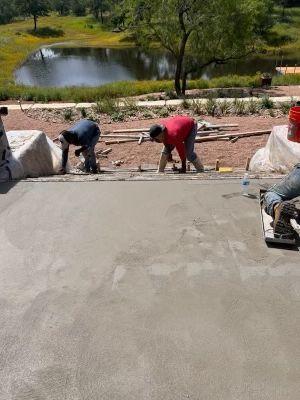 A group of construction workers are working on a concrete driveway.
