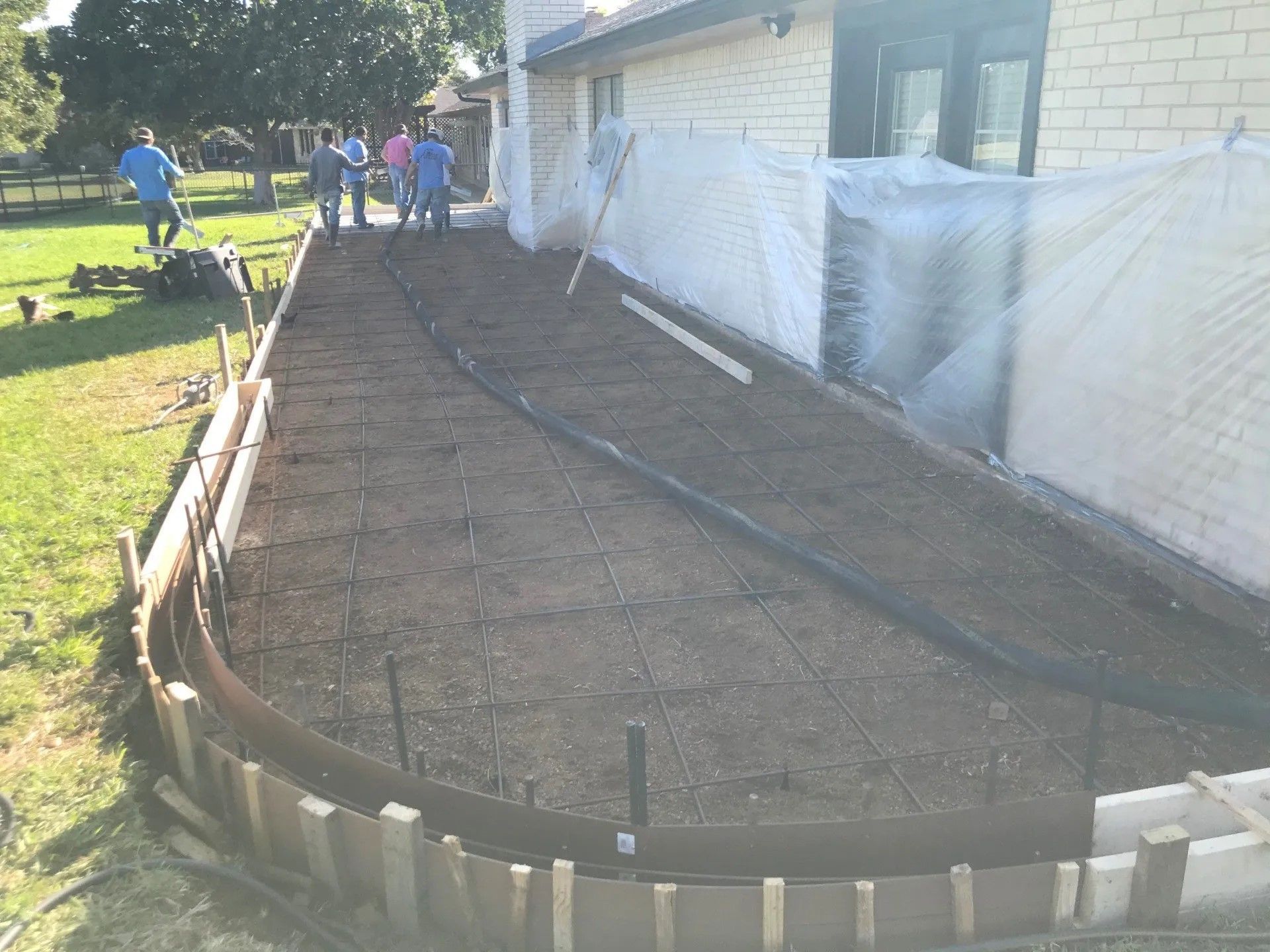 A group of people are working on a sidewalk in front of a house
