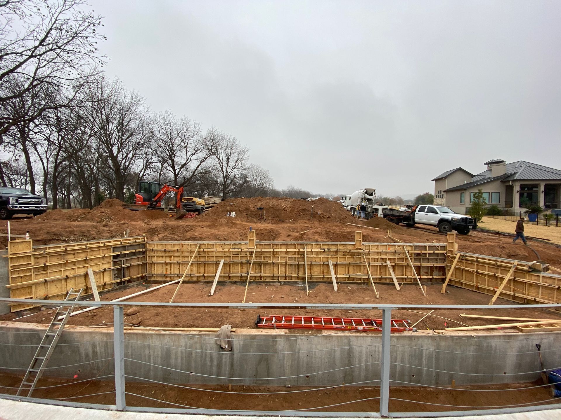 A large concrete pool is being built in the middle of a dirt field.