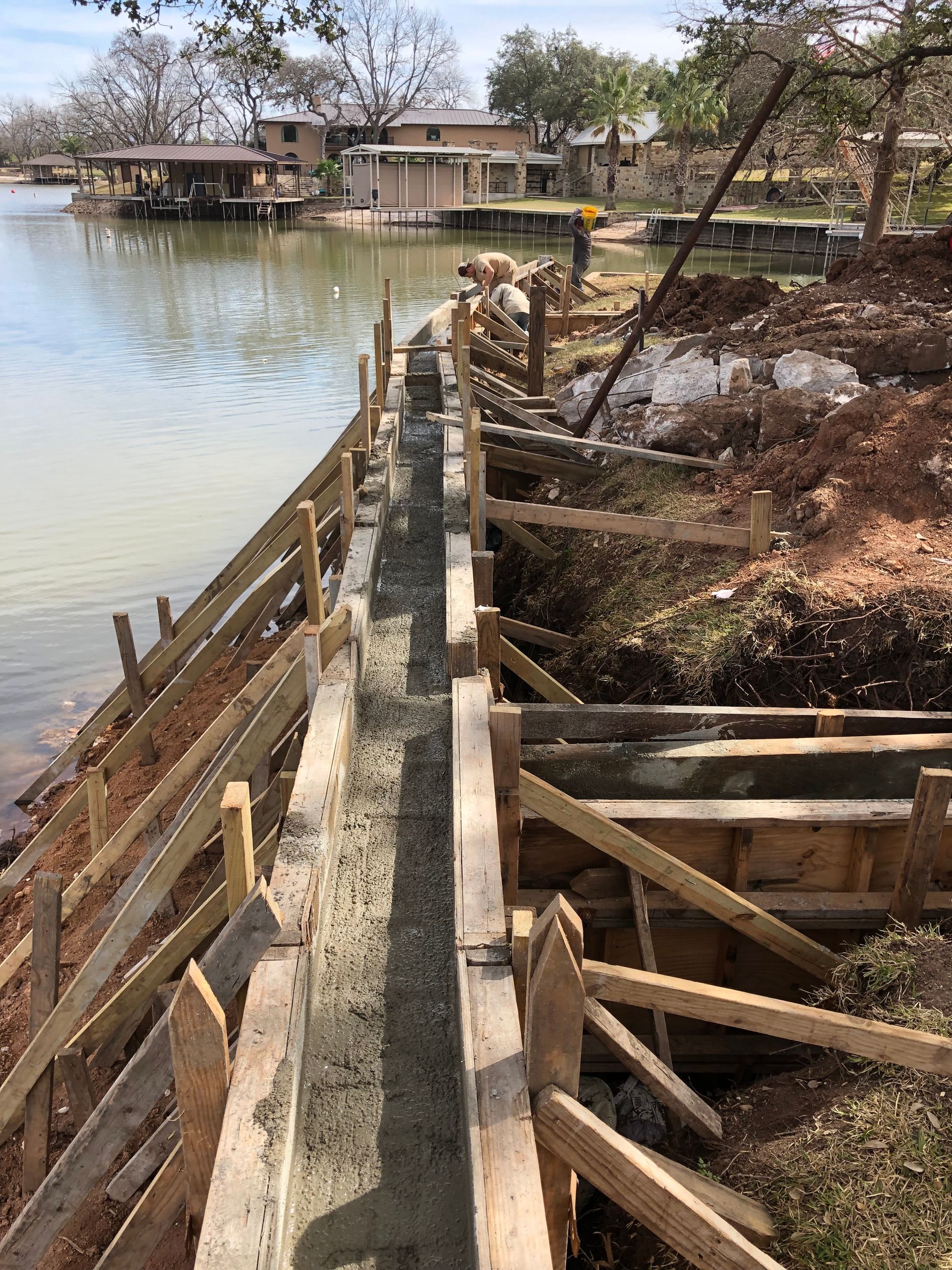 A concrete wall is being built next to a body of water.
