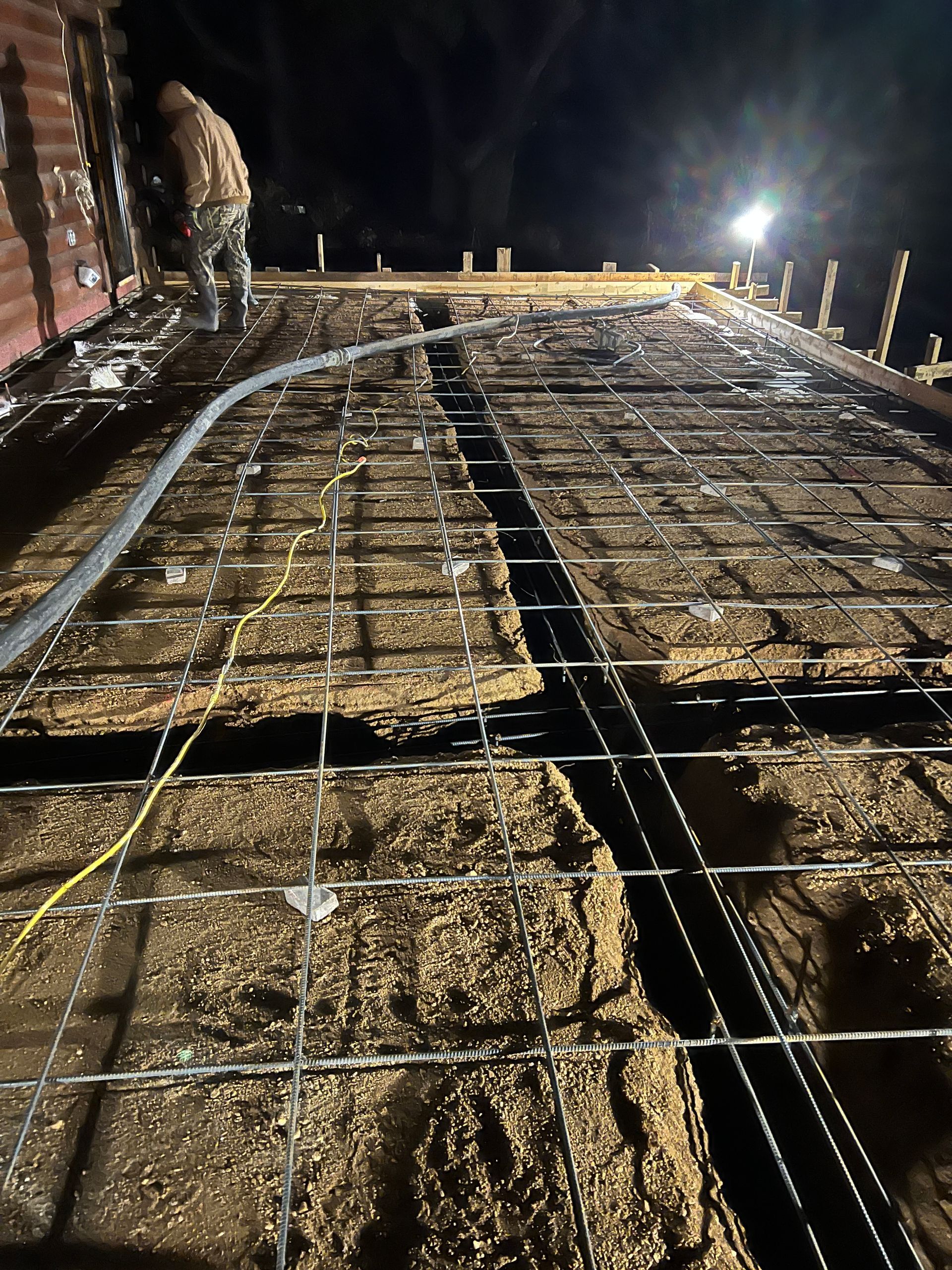 A man is working on a concrete floor at night.