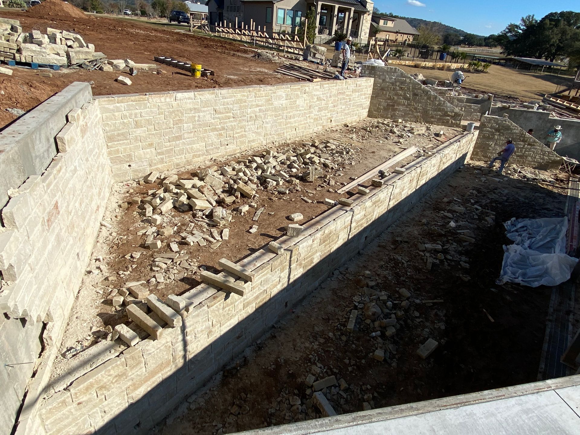 A large concrete wall is being built on top of a dirt field.