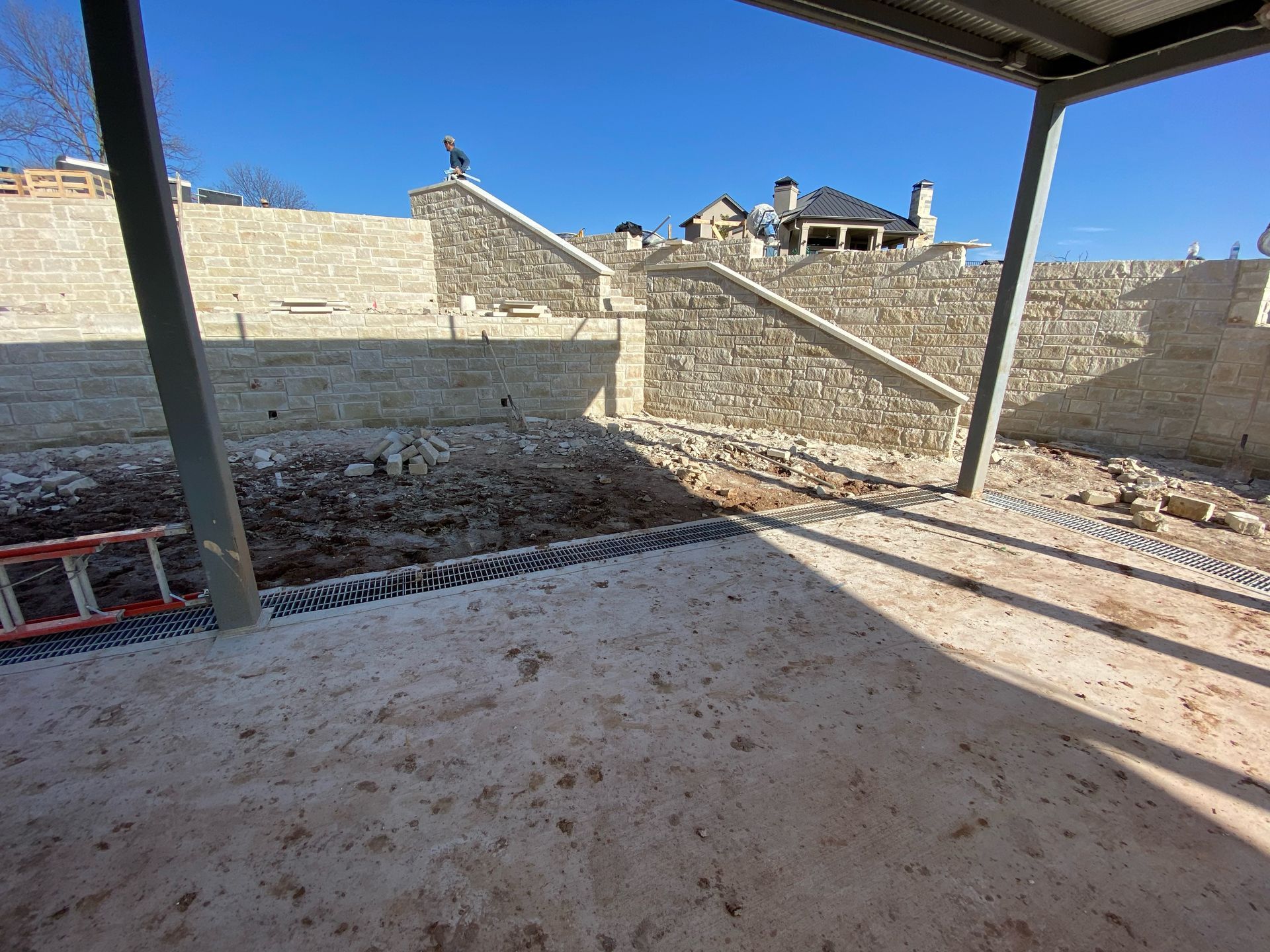 A ladder is sitting on the ground in front of a stone wall.