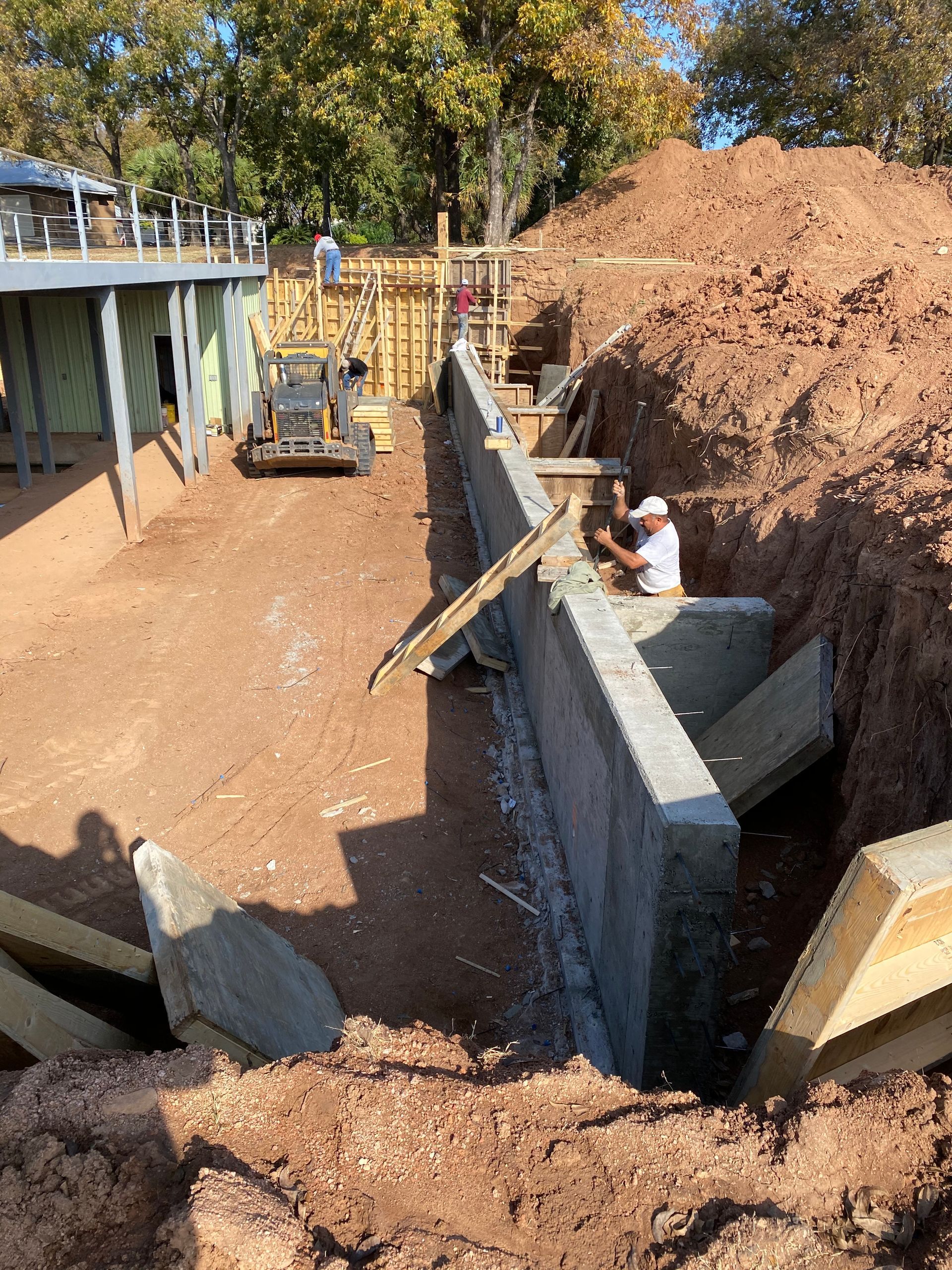 A construction site with a bulldozer and a man working on a wall.