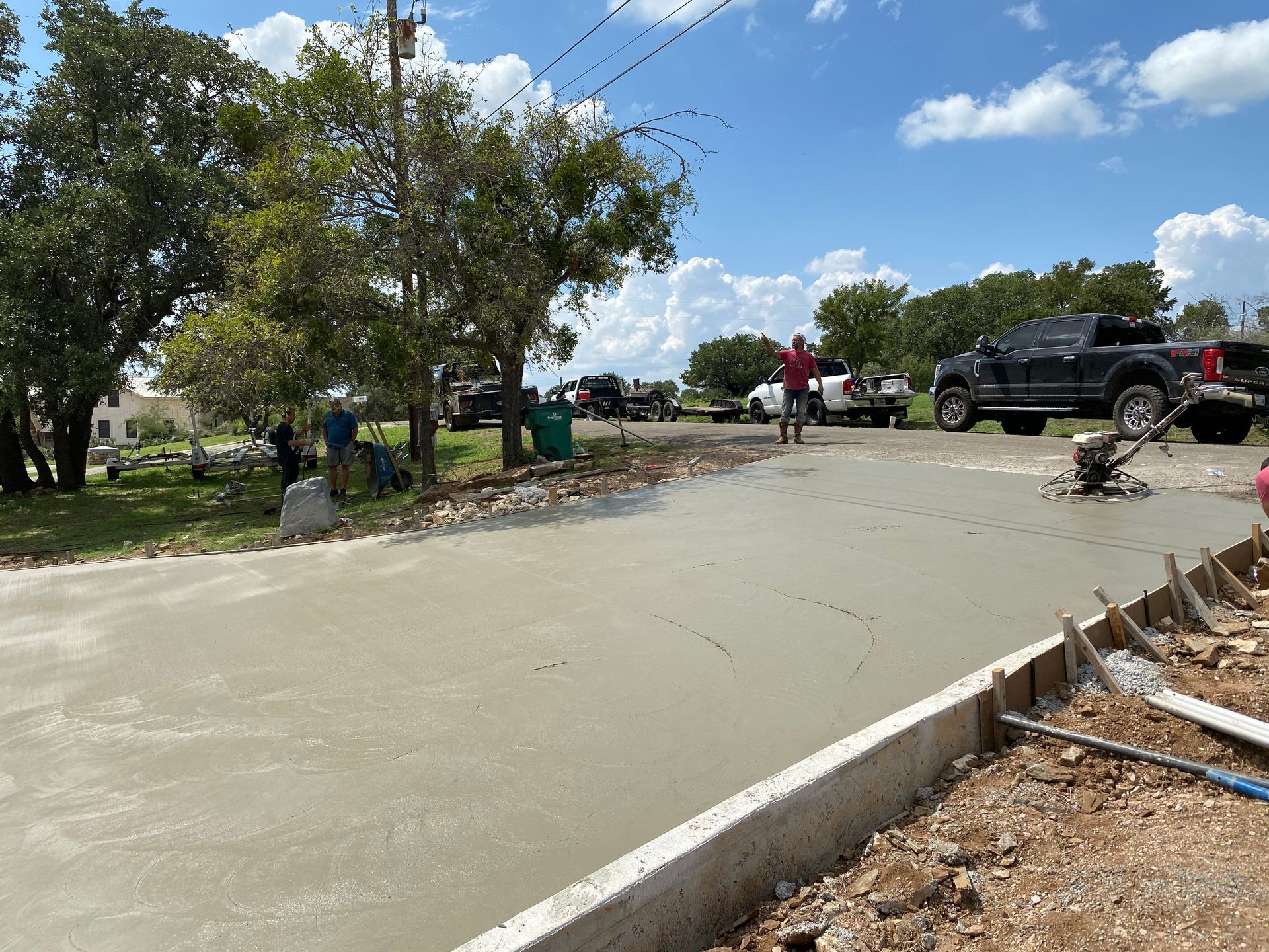 A concrete driveway is being poured on a sunny day.