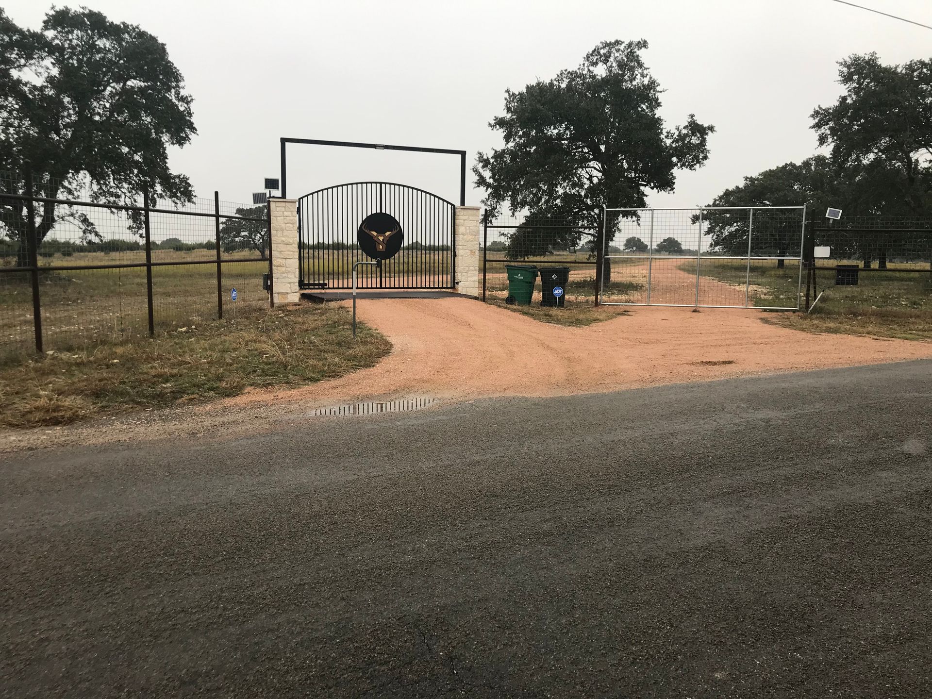 A gate with a wreath on it is on the side of a road