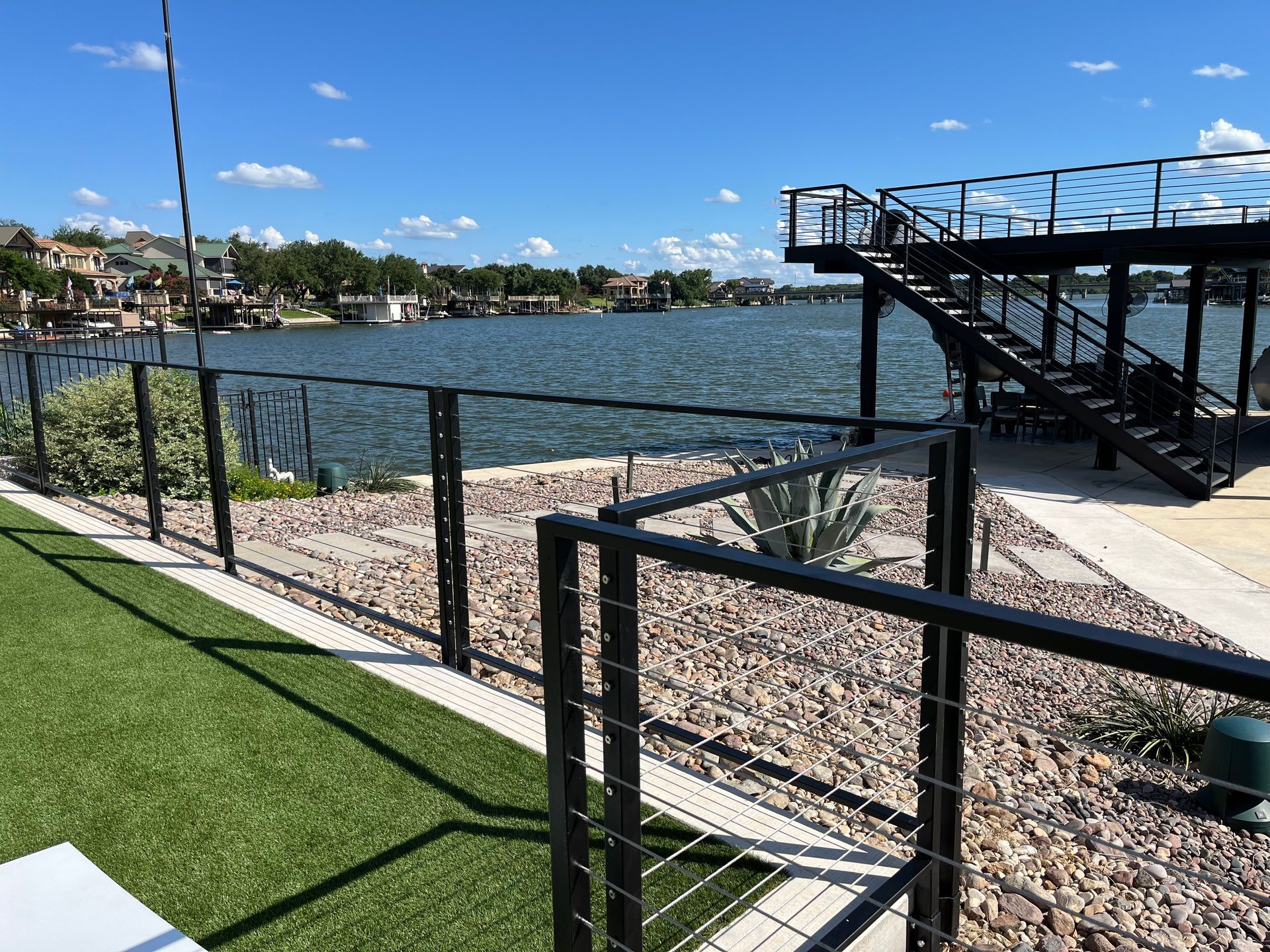 A fence with stairs leading up to a dock overlooking a lake.
