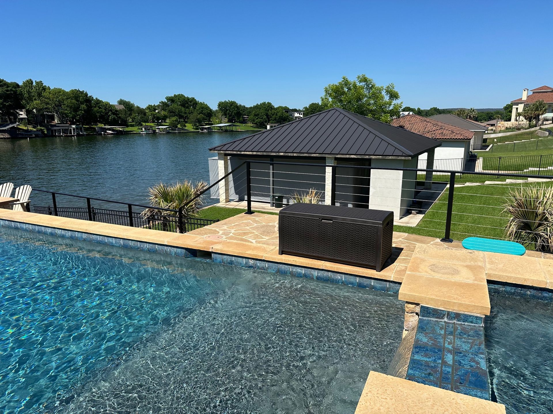 A swimming pool with a house in the background and a lake in the background.
