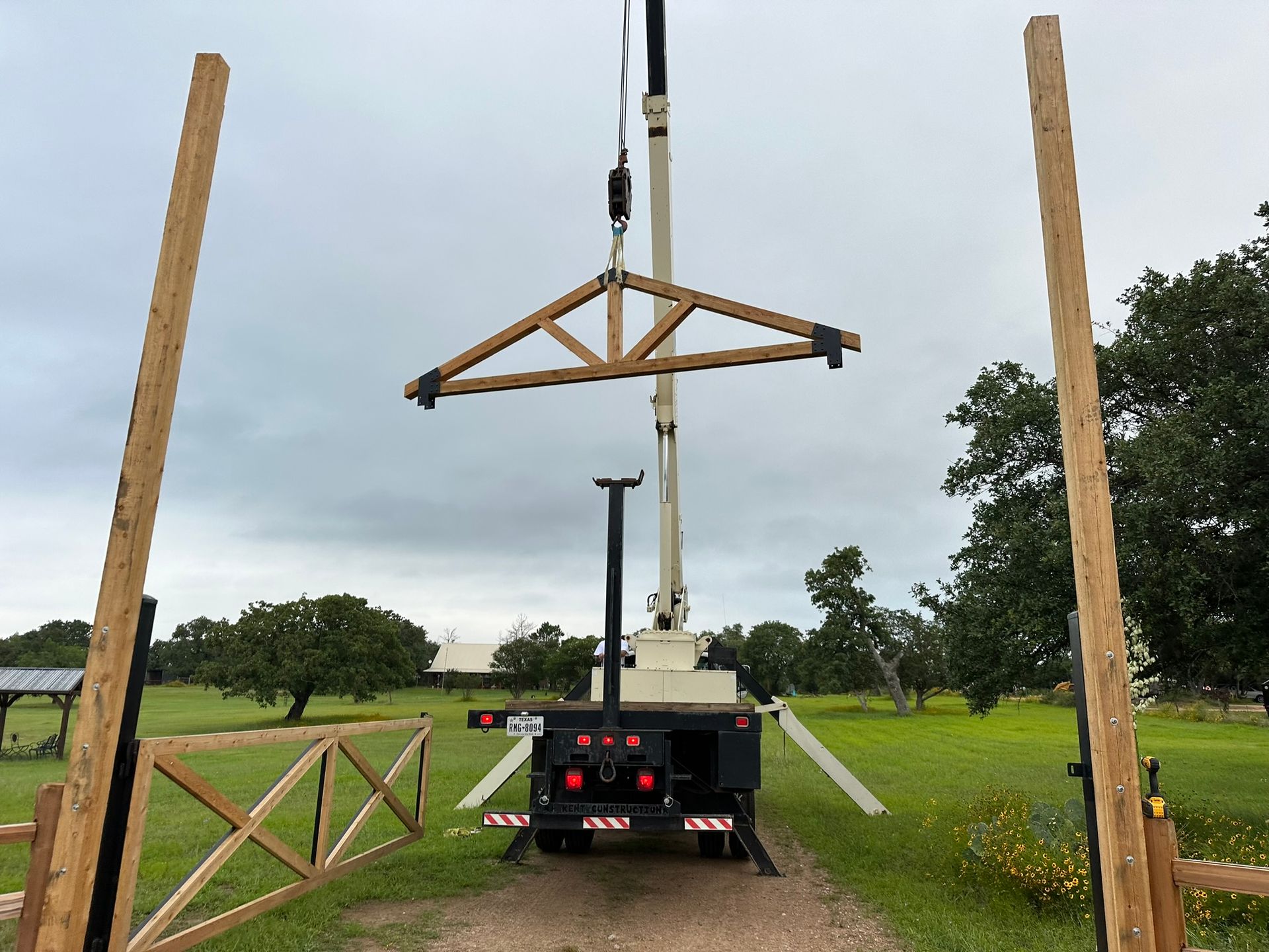 A crane is lifting a wooden structure in a field.