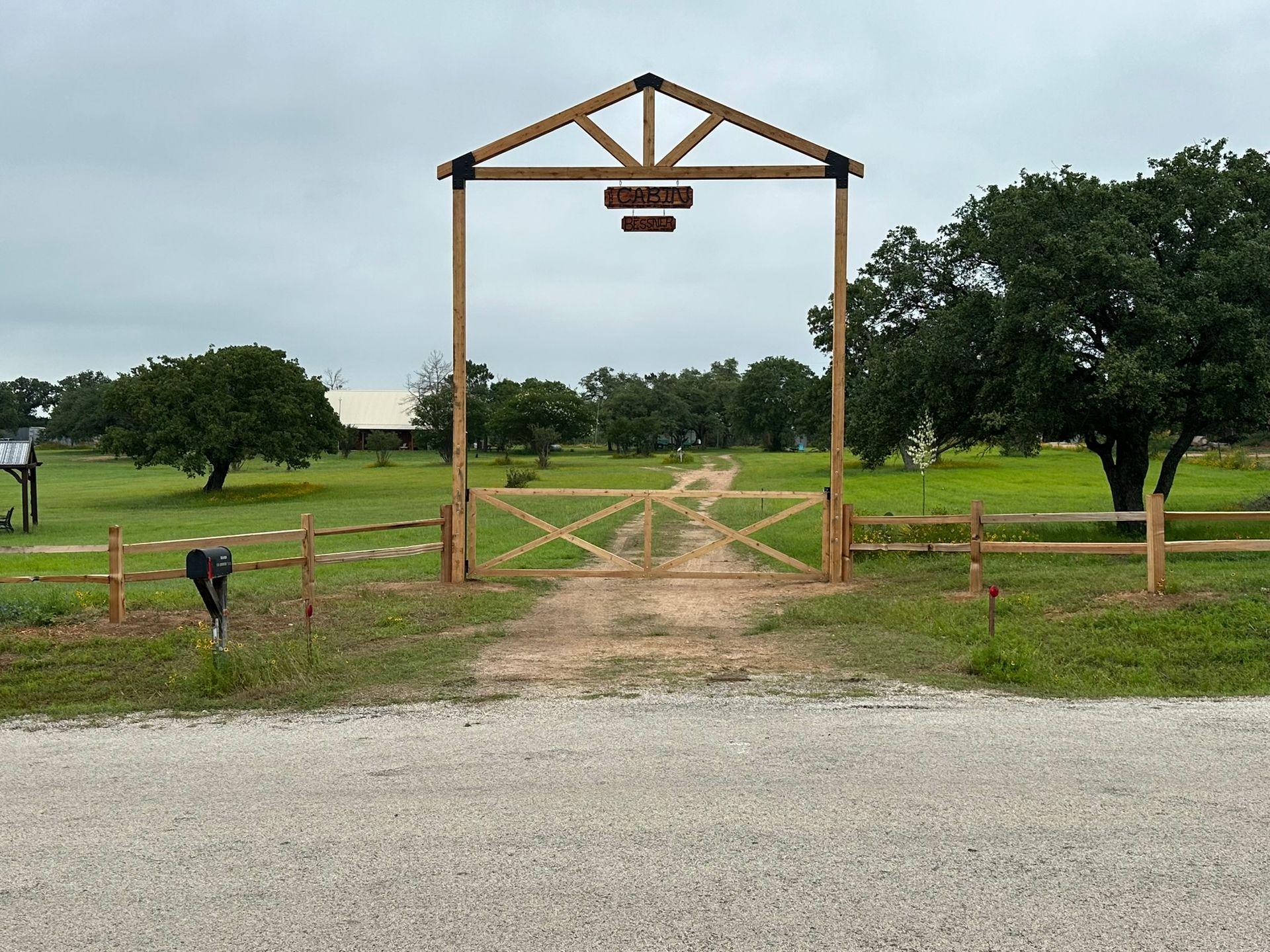 A horse is standing in front of a wooden gate in a field.